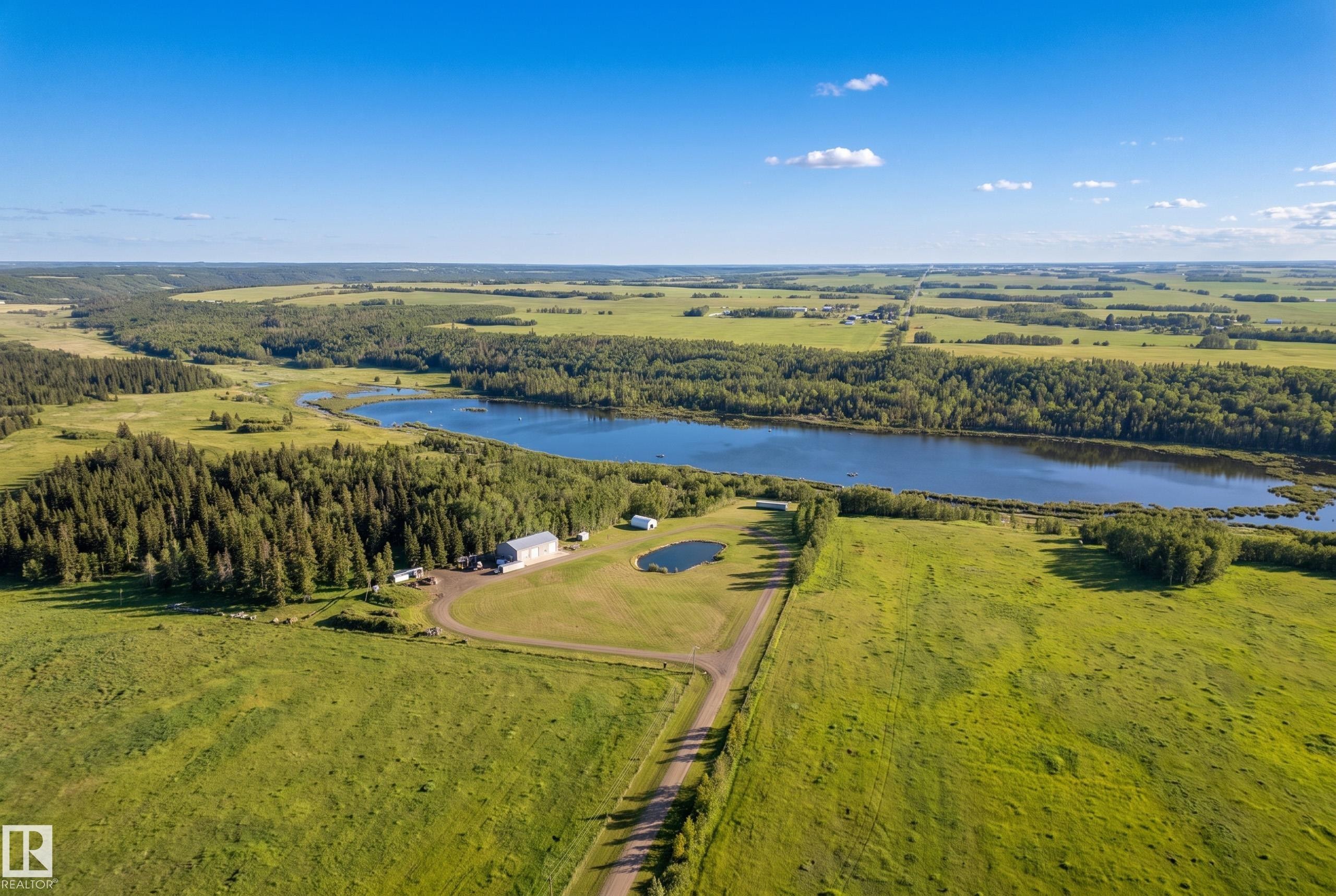 Expansive rural property featuring a large lake, dense forest, open fields, a substantial outbuilding, and a private pond - 49279 Rge Rd 240, Rural Leduc County, AB