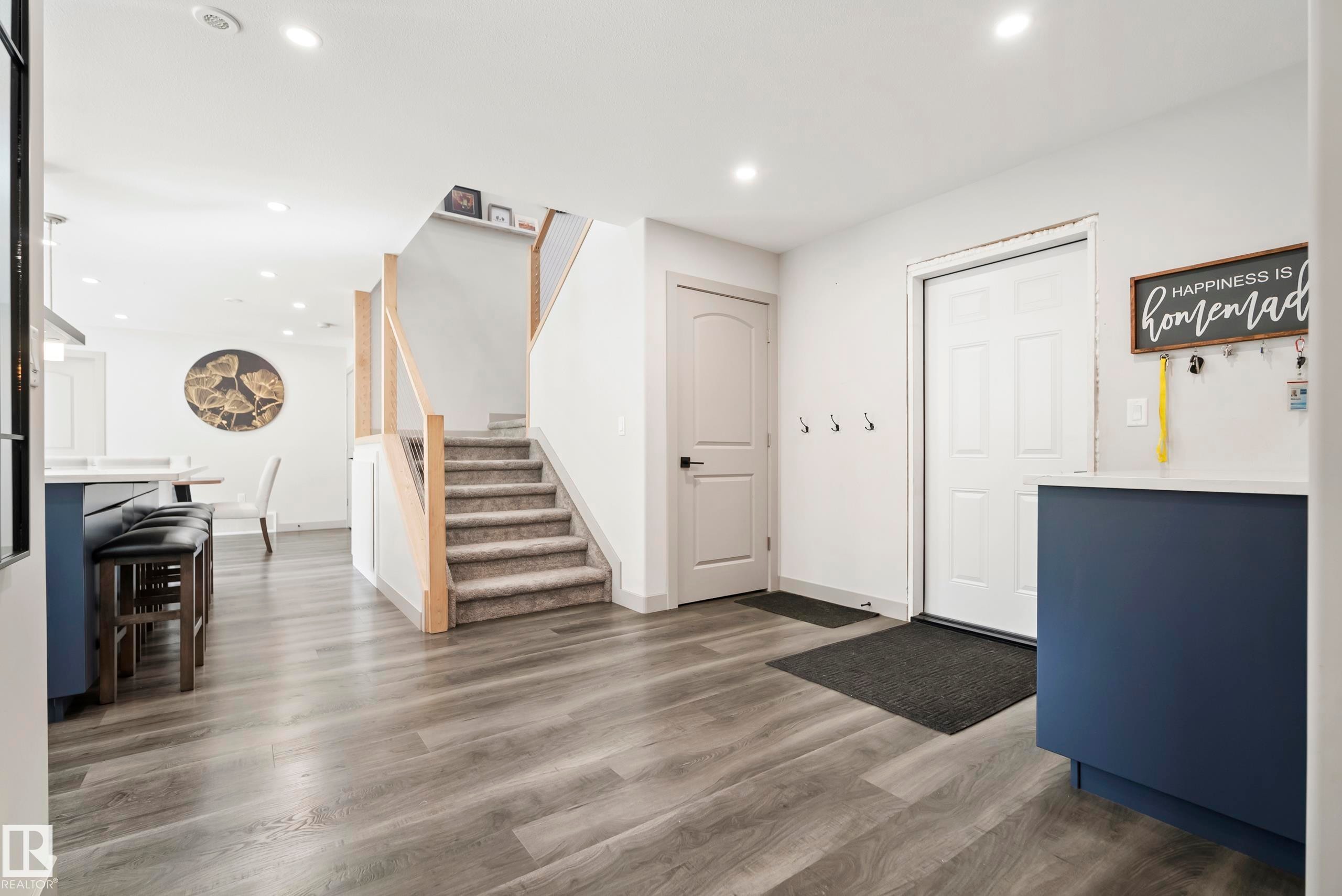 Wood-finish flooring, recessed lighting, and a staircase with wood railing and carpeted treads - 49279 Rge Rd 240, Rural Leduc County, AB