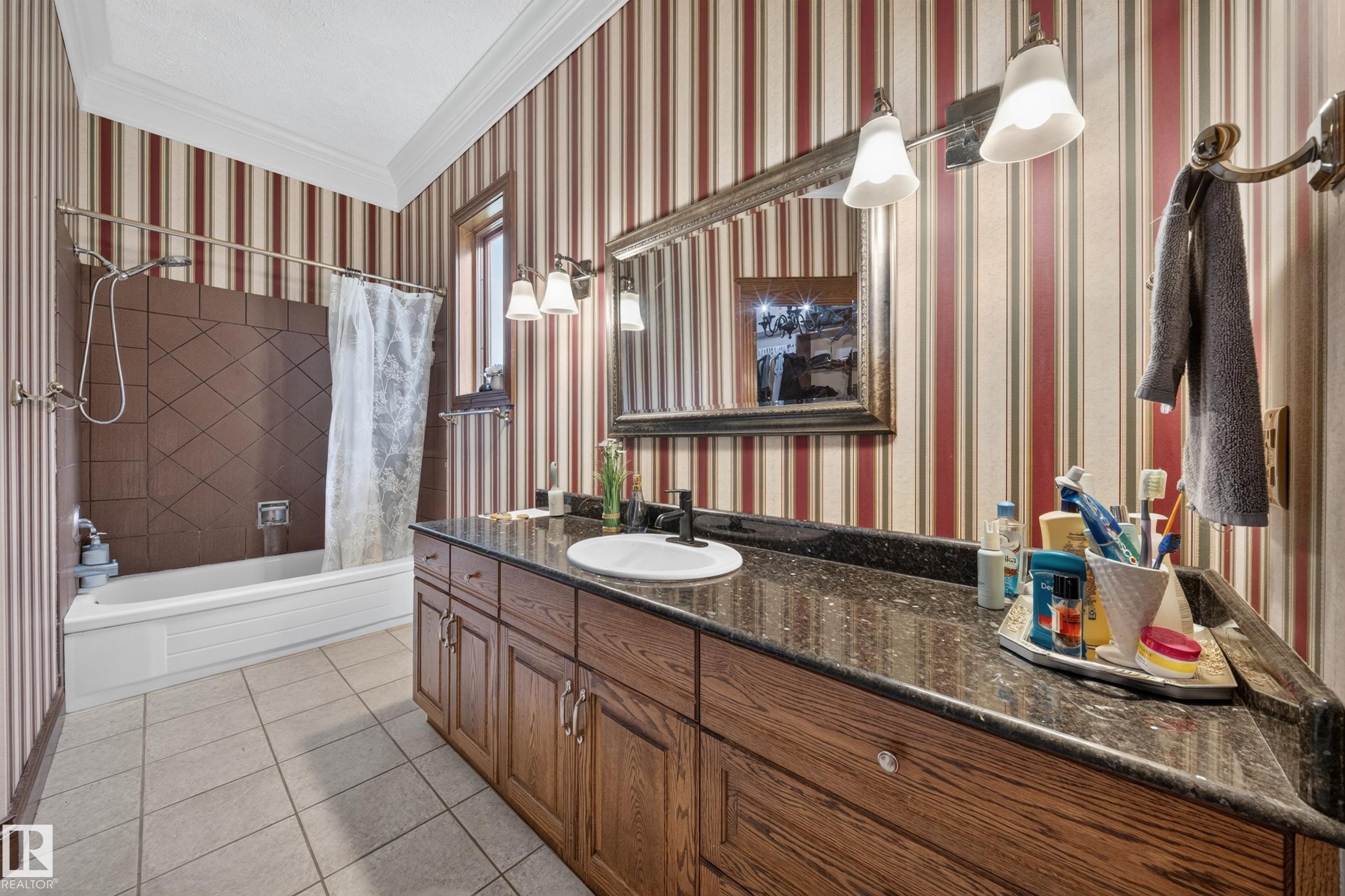 Oak vanity with a dark speckled countertop, undermount sink, and wall-mounted light fixture - 719 65 Ave Nw, Edmonton, AB
