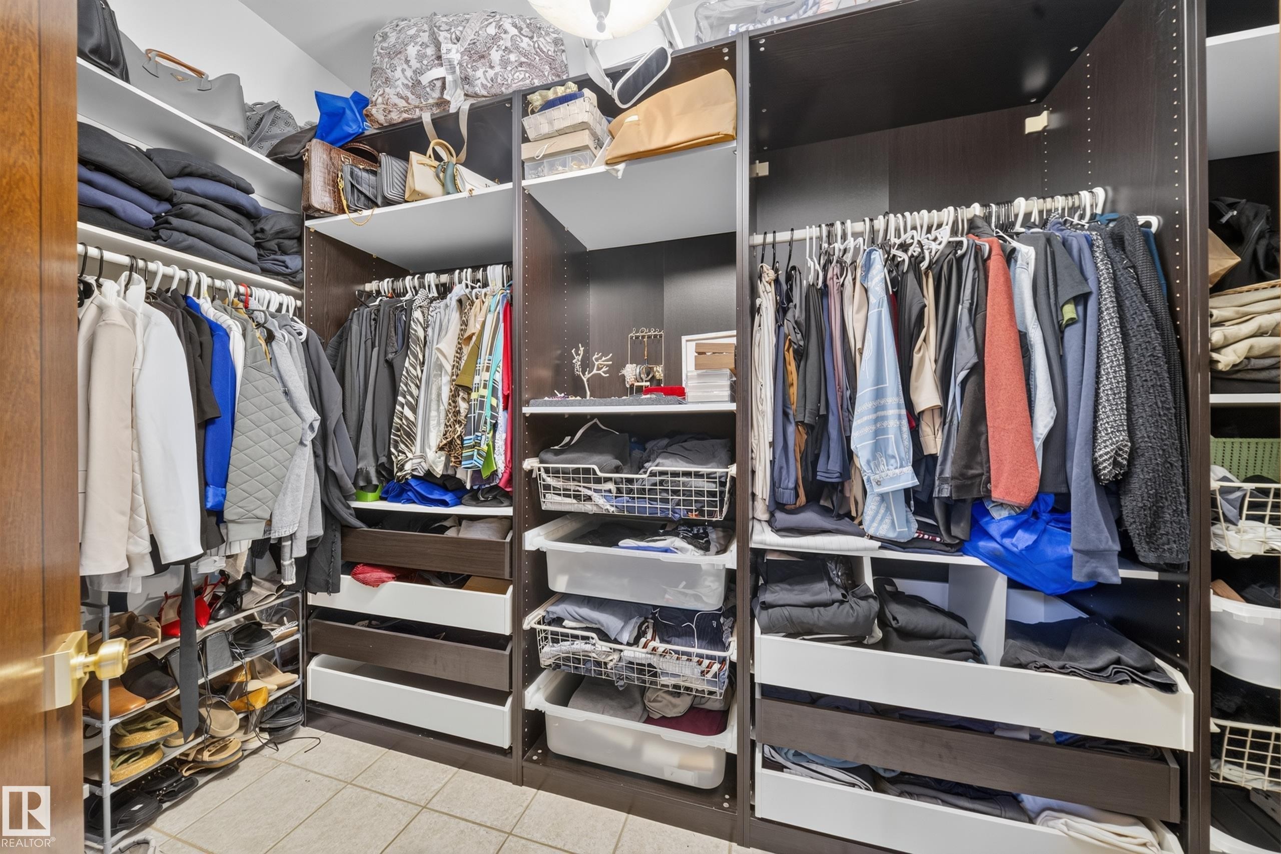 Custom closet system featuring dark wood-finish cabinetry, multiple hanging rods, integrated shelving, and pull-out drawers - 719 65 Ave Nw, Edmonton, AB