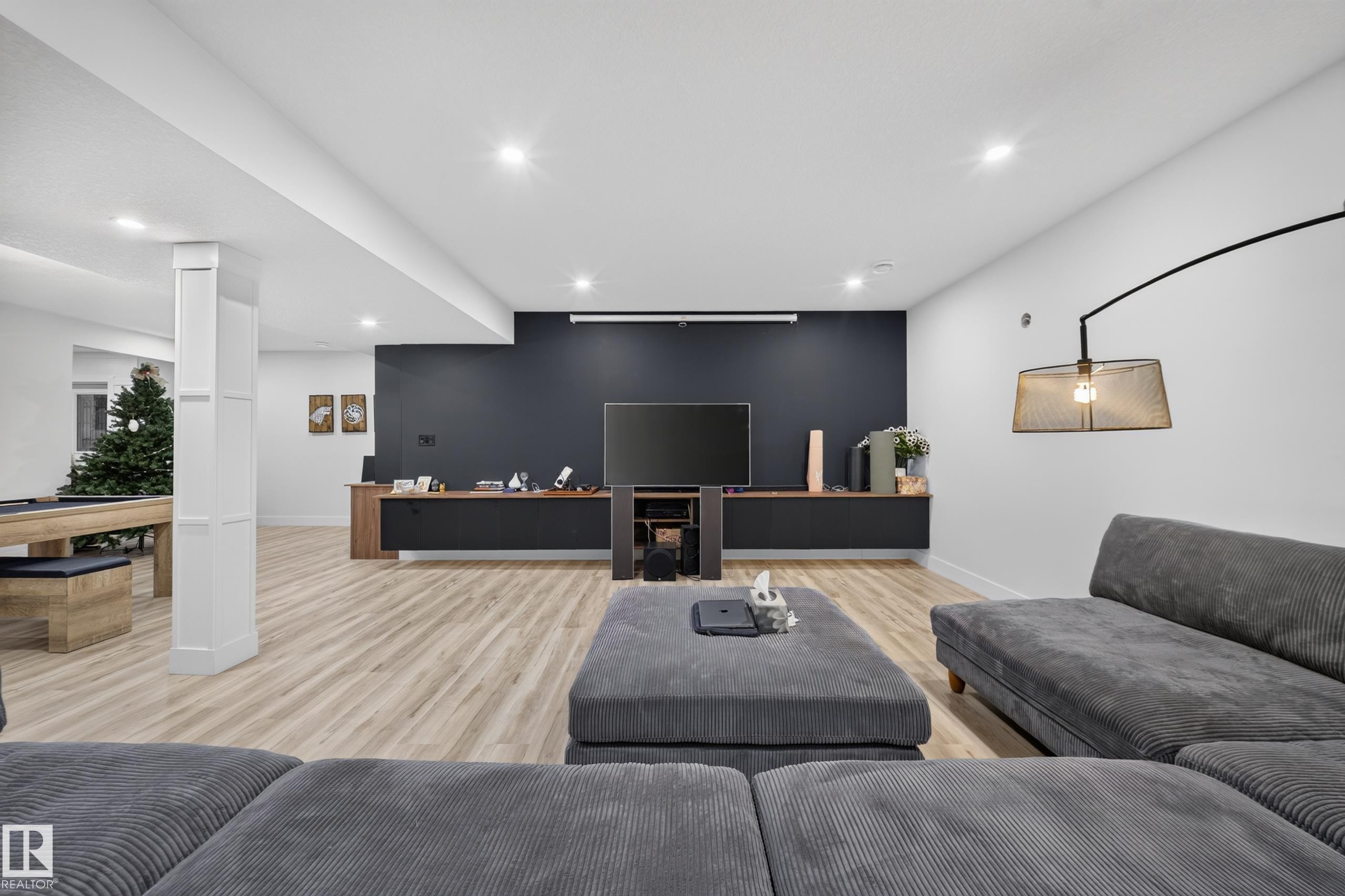 Recessed lighting, wood-finish flooring, built-in media console, accent wall, and wall-mounted light fixture - 719 65 Ave Nw, Edmonton, AB