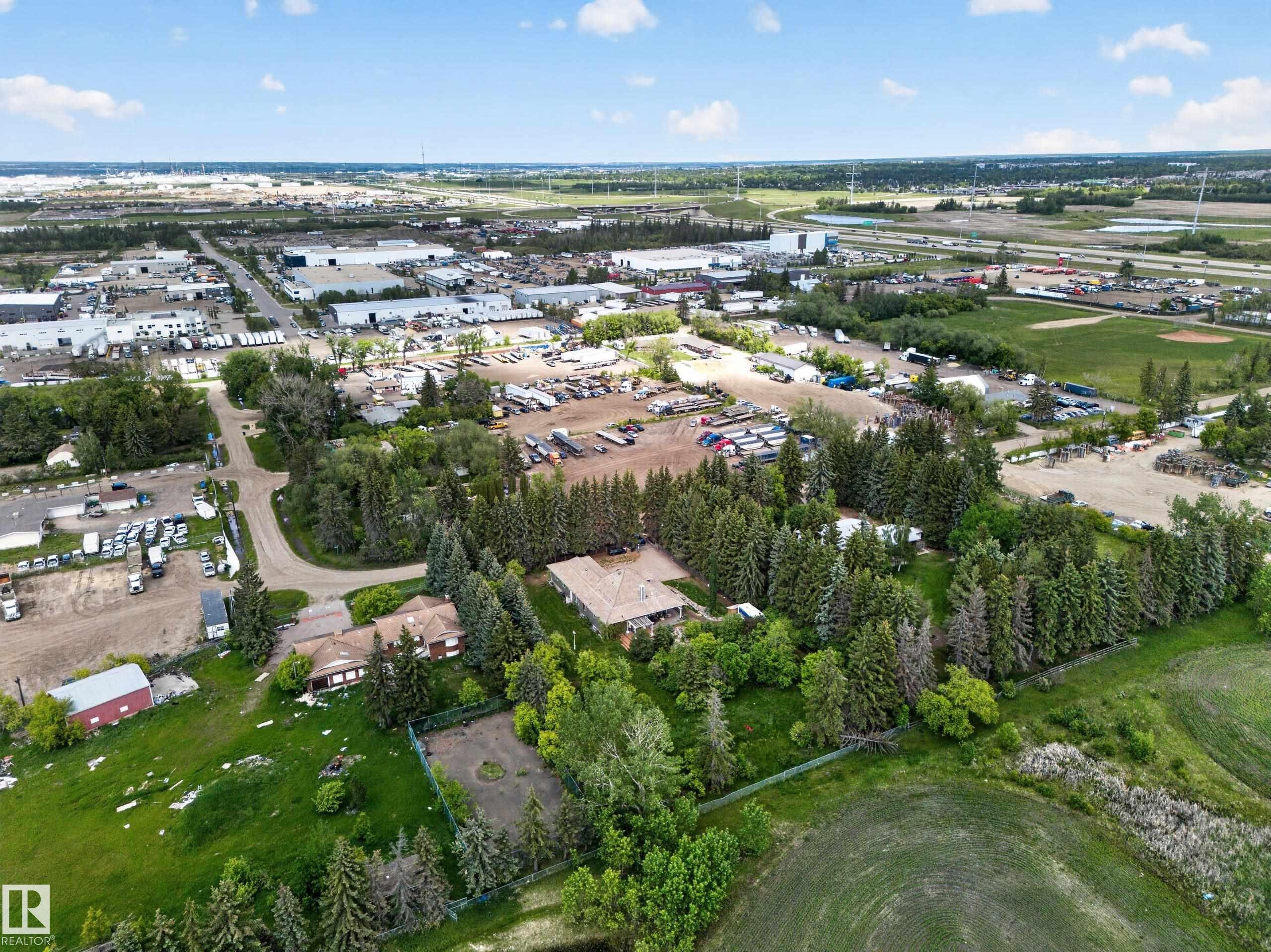 Expansive property featuring a main residence, mature evergreen trees, and a detached outbuilding - 719 65 Ave Nw, Edmonton, AB