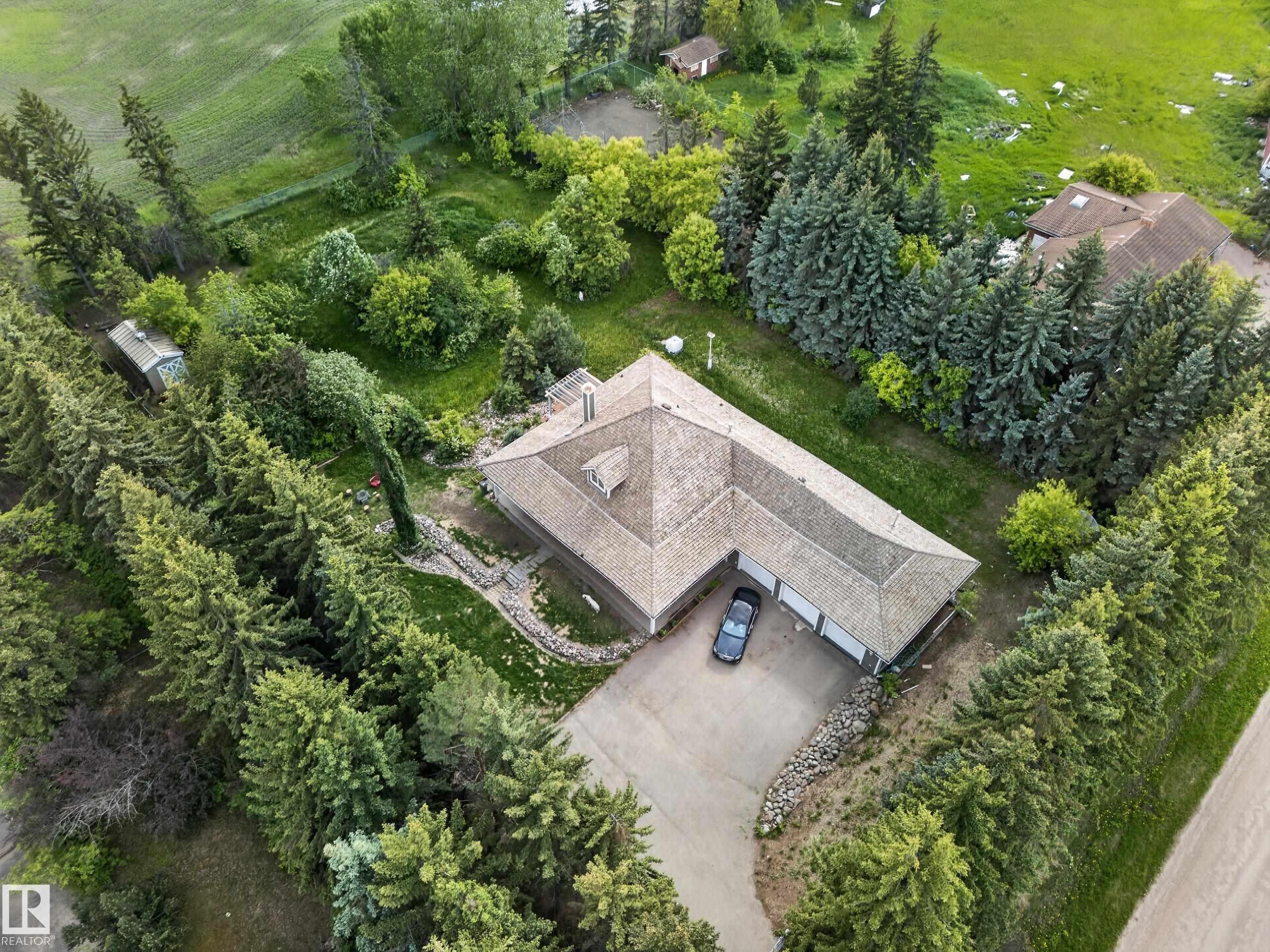 L-shaped property with a multi-car garage, surrounded by mature evergreen trees - 719 65 Ave Nw, Edmonton, AB