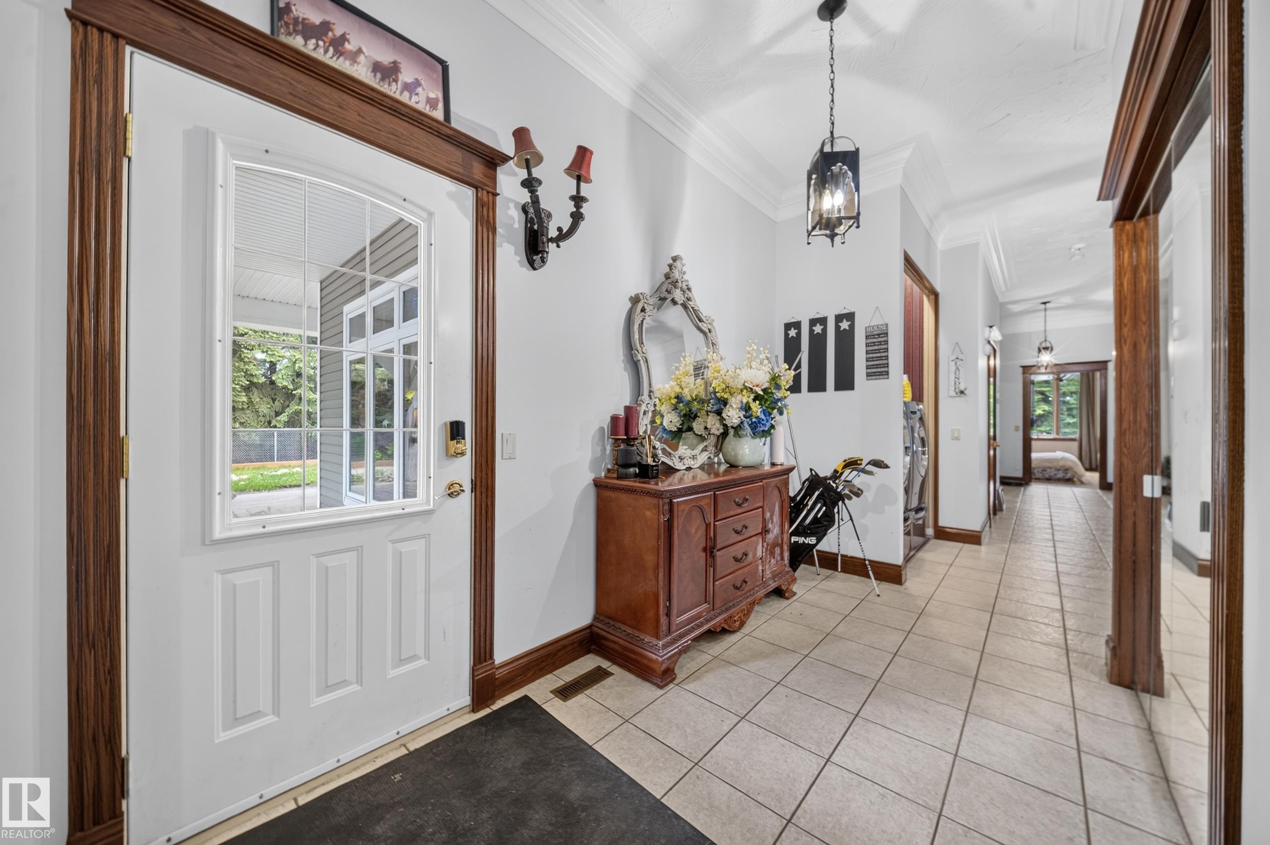 White paneled entry door with an arched window, dark wood-finish trim, tiled flooring, and crown molding - 719 65 Ave Nw, Edmonton, AB