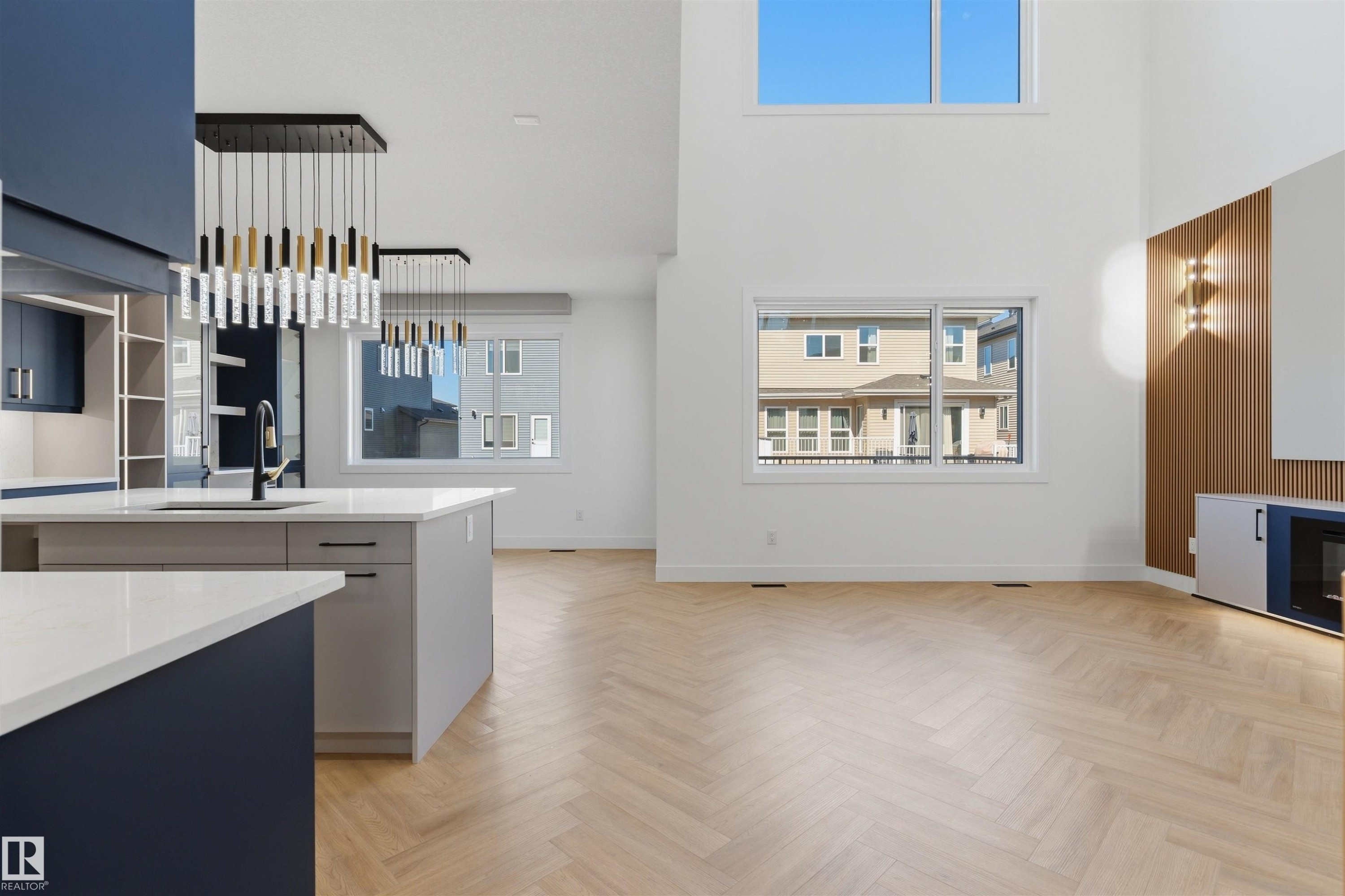 Vaulted ceilings with an upper transom window, herringbone wood-finish flooring, two-tier kitchen island with countertop, and integrated built-in cabinetry - 2720 63 Avenue, Rural Leduc County, AB