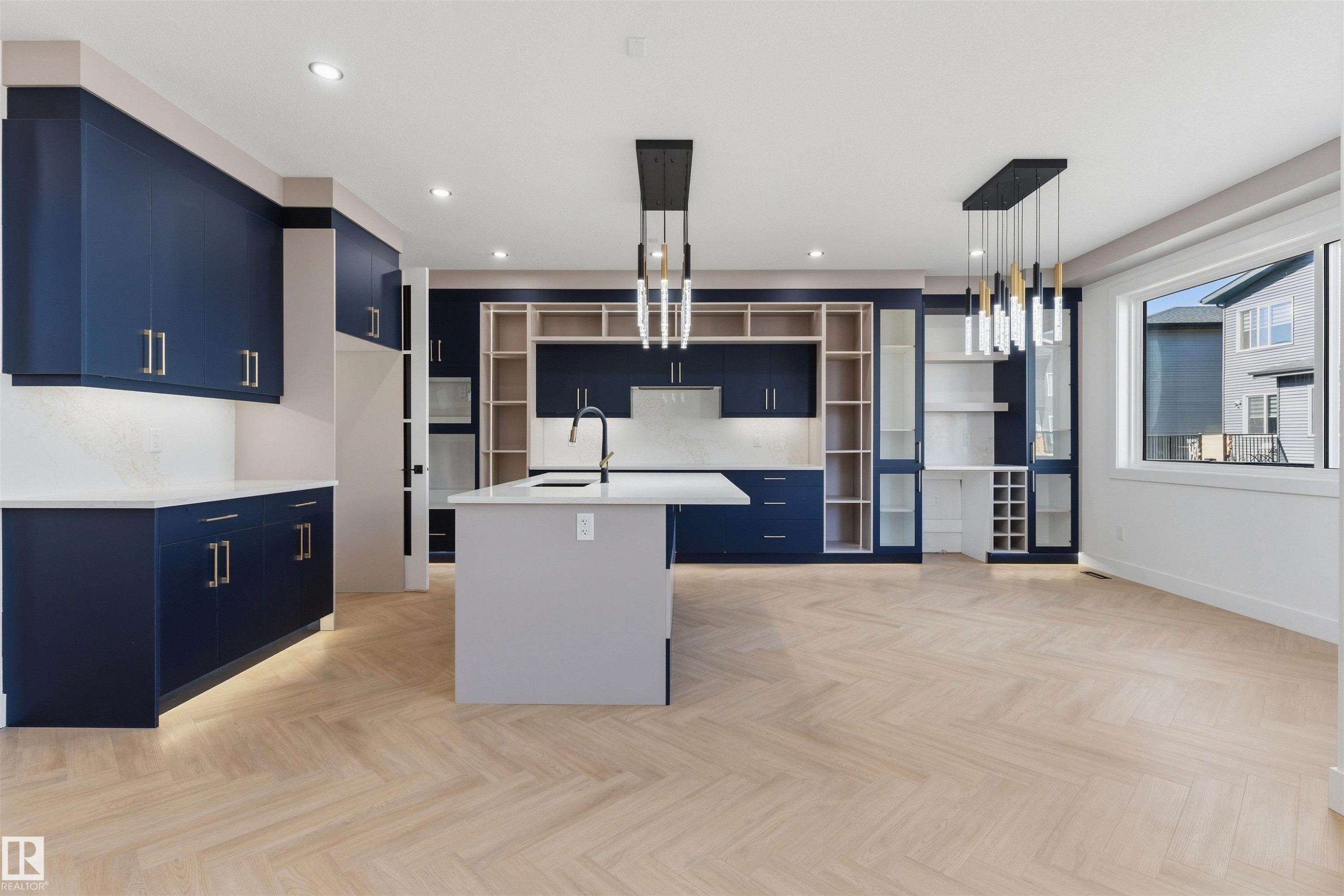 Kitchen with blue cabinetry, a central island, light wood-finish herringbone flooring, and contemporary pendant lighting - 2720 63 Avenue, Rural Leduc County, AB