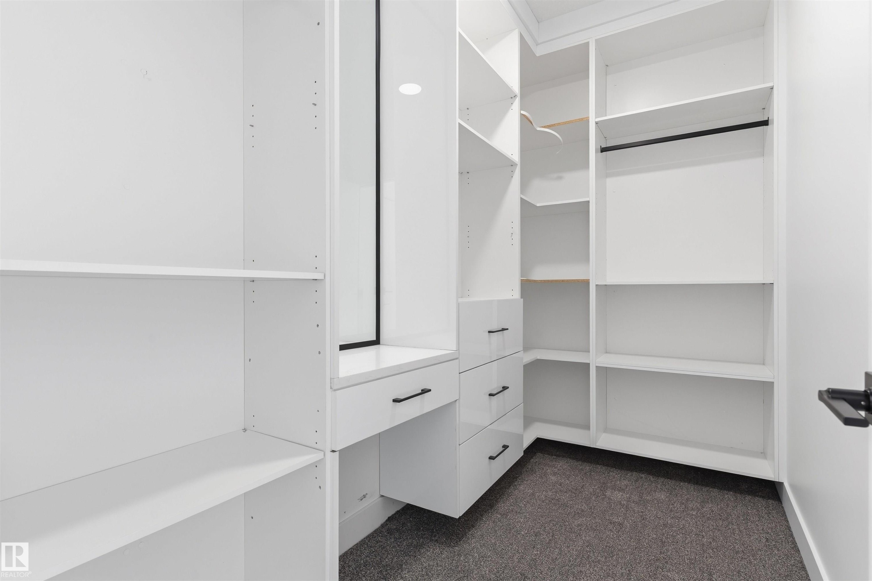Custom white cabinetry with multiple shelving units, built-in drawers, hanging rods, and a dressing area - 2720 63 Avenue, Rural Leduc County, AB