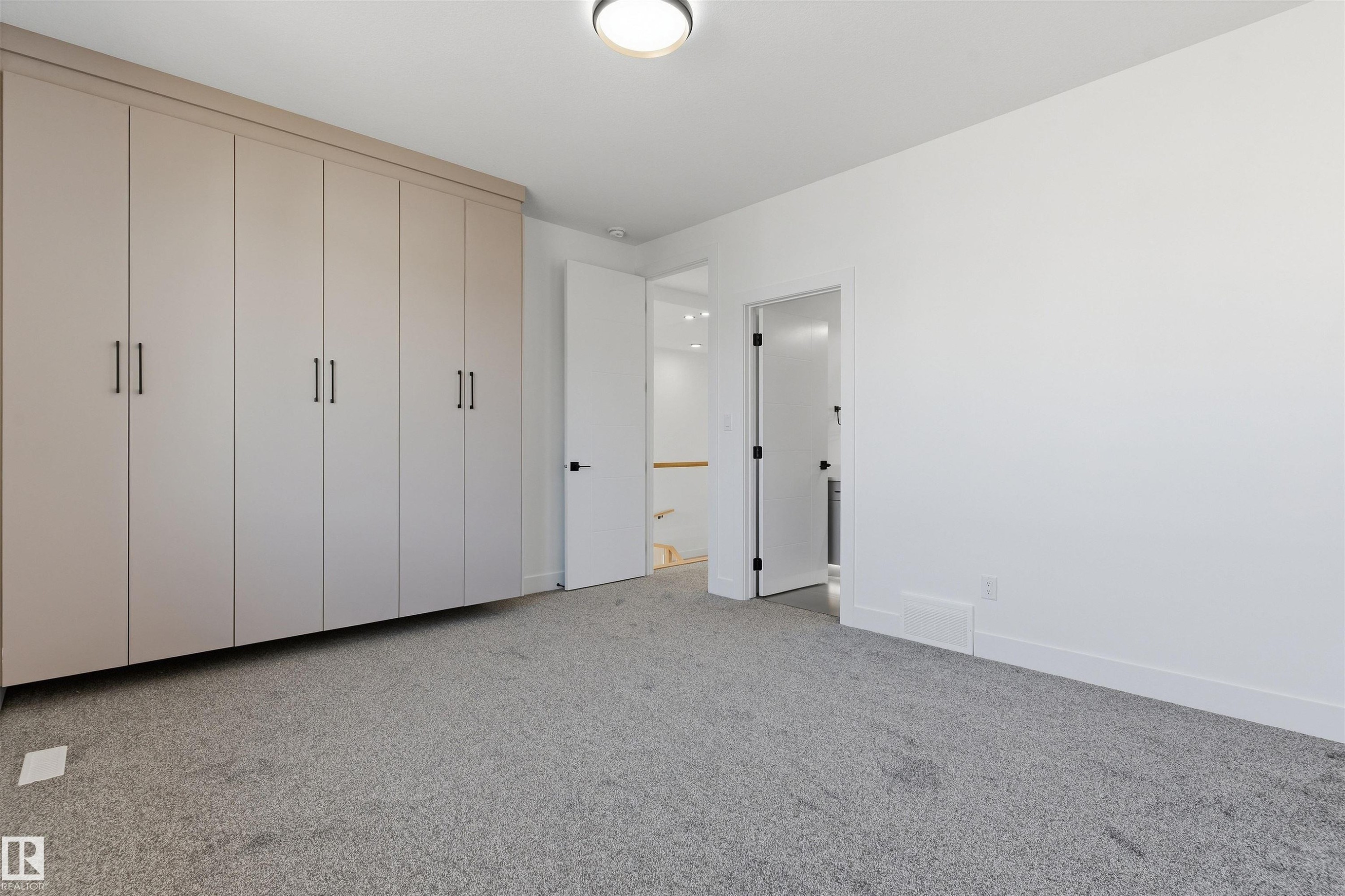 Built-in cabinetry with matte black hardware, grey-toned carpeting, and white painted walls - 2720 63 Avenue, Rural Leduc County, AB