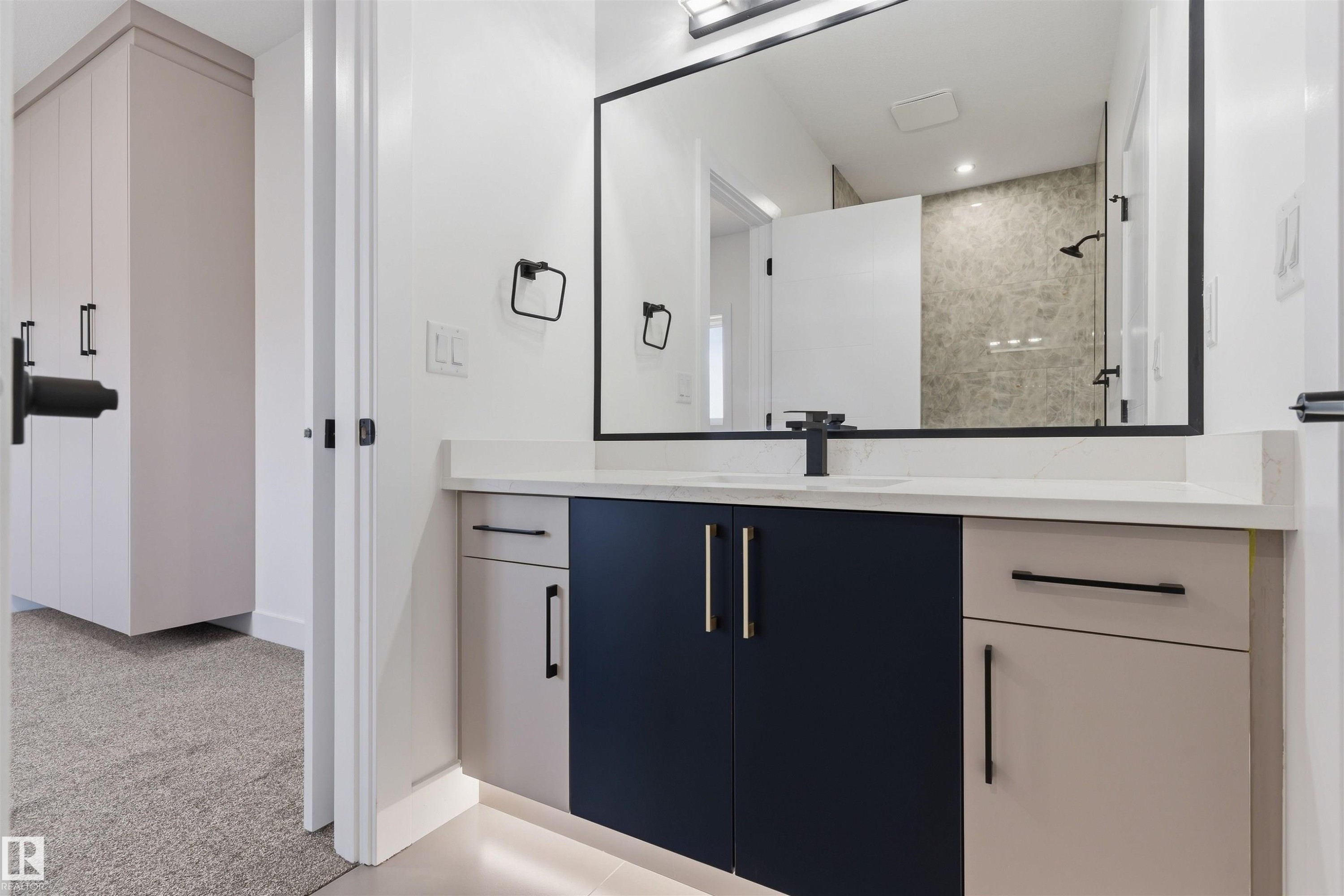 Floating vanity with a light-colored countertop, integrated sink, and matte black faucet - 2720 63 Avenue, Rural Leduc County, AB