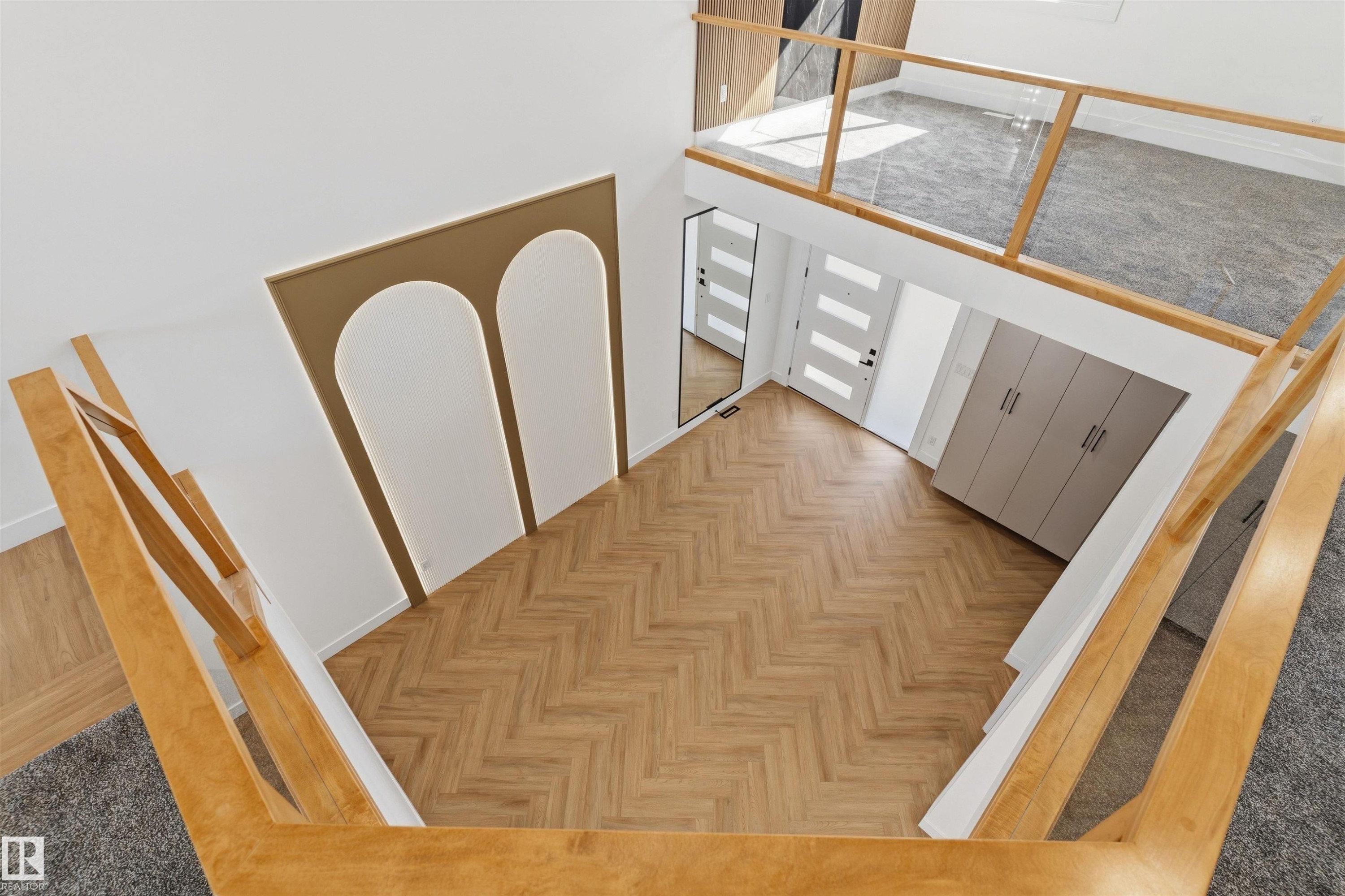 Open concept entrance with herringbone wood-finish flooring, a decorative wall panel with integrated lighting, and a grey built-in storage unit - 2720 63 Avenue, Rural Leduc County, AB