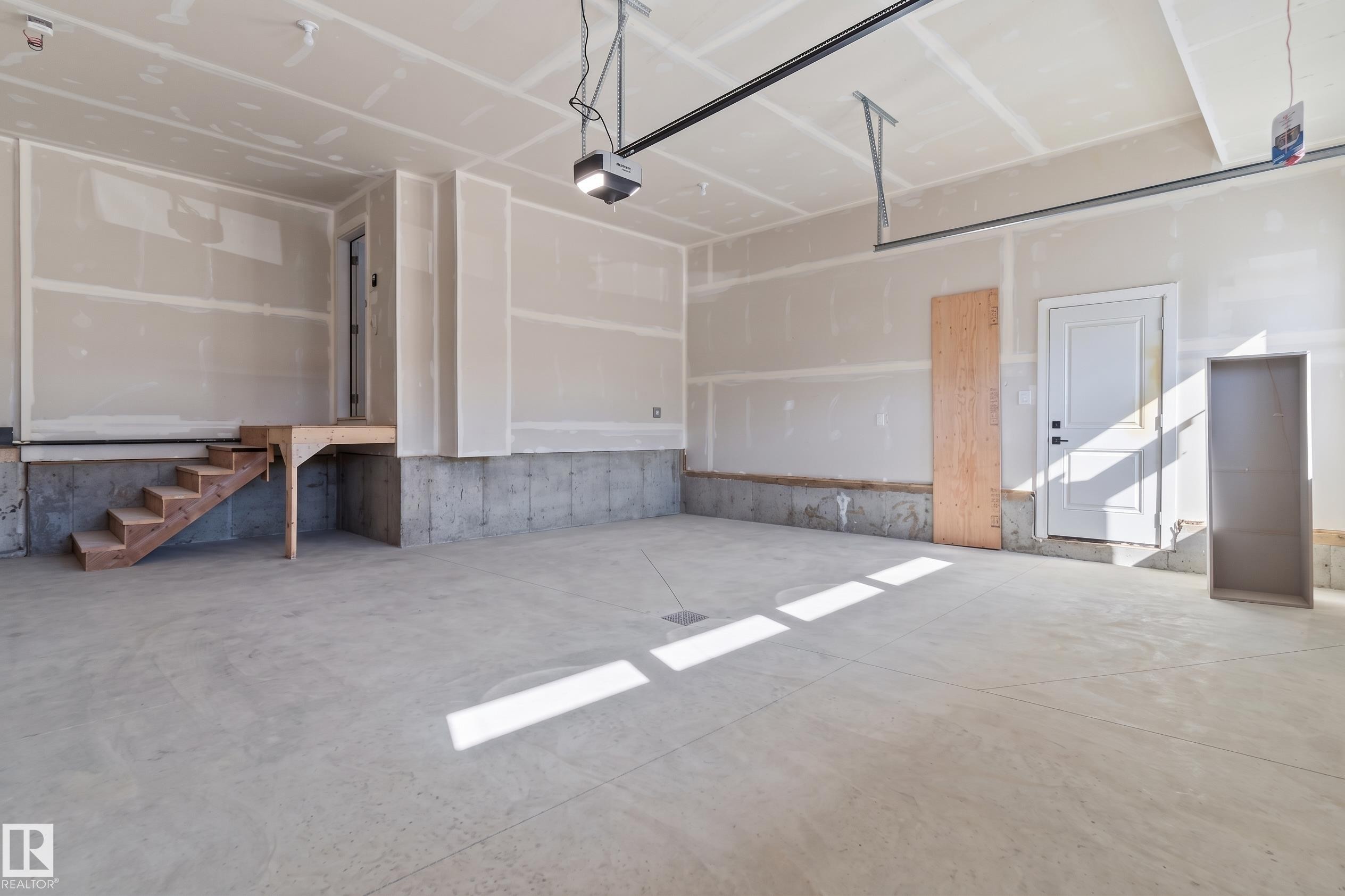 Concrete flooring, drywall walls, overhead lighting, garage door track system, and interior access door - 2720 63 Avenue, Rural Leduc County, AB
