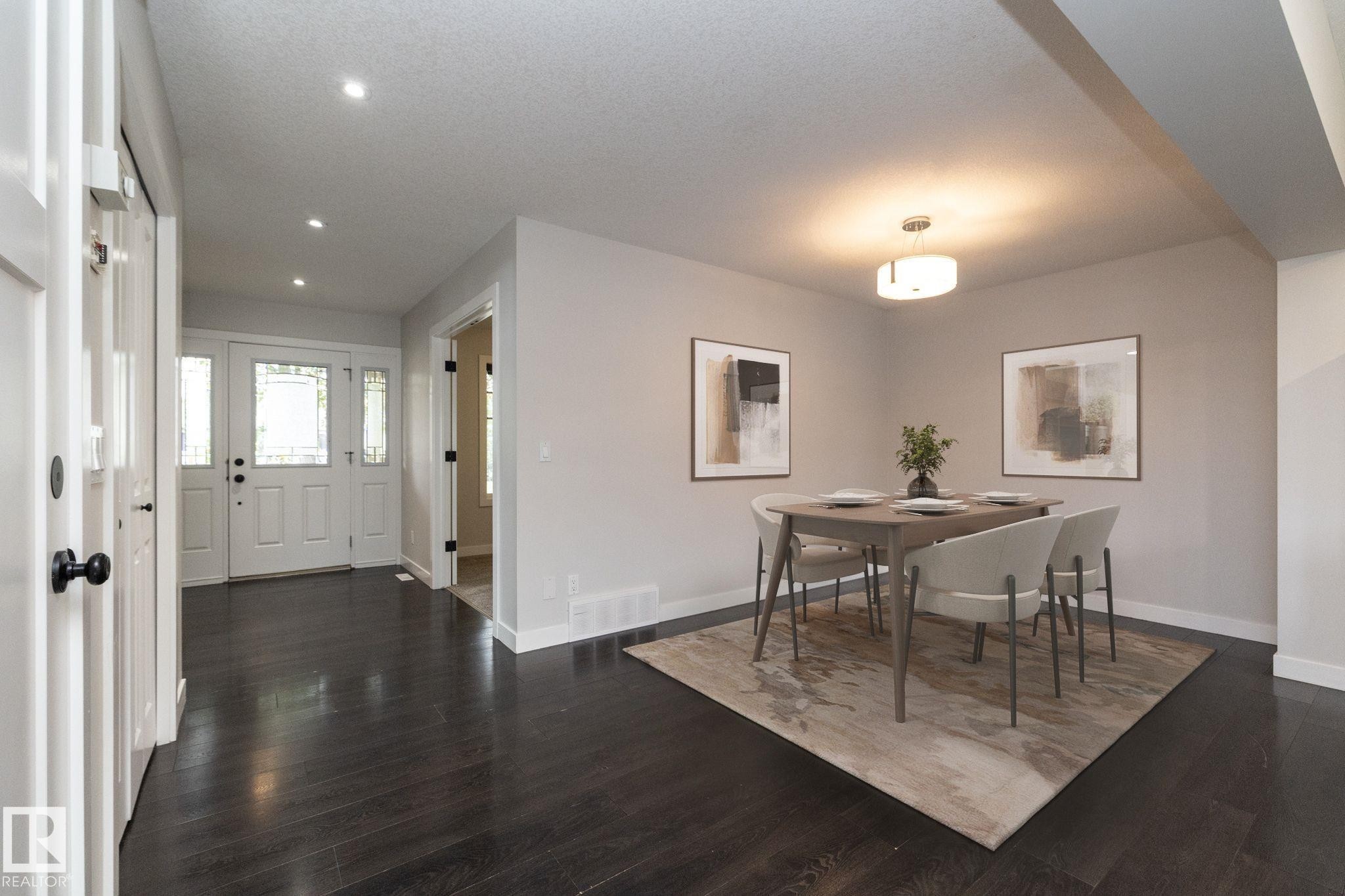 Dark wood-finish flooring throughout, recessed lighting, and a white front entry door with decorative glass panels - 55 Michigan Street, Devon, AB