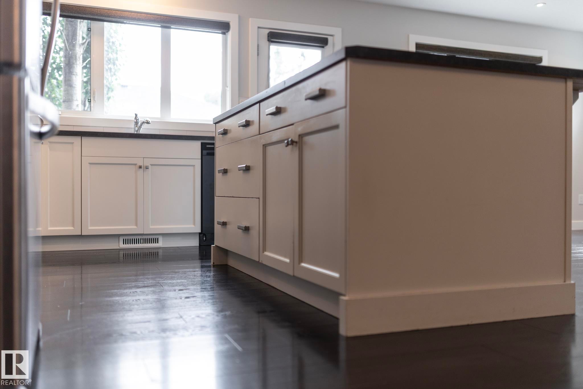 Kitchen island with countertop, under-sink cabinetry, built-in dishwasher, and wood-finish flooring - 55 Michigan Street, Devon, AB
