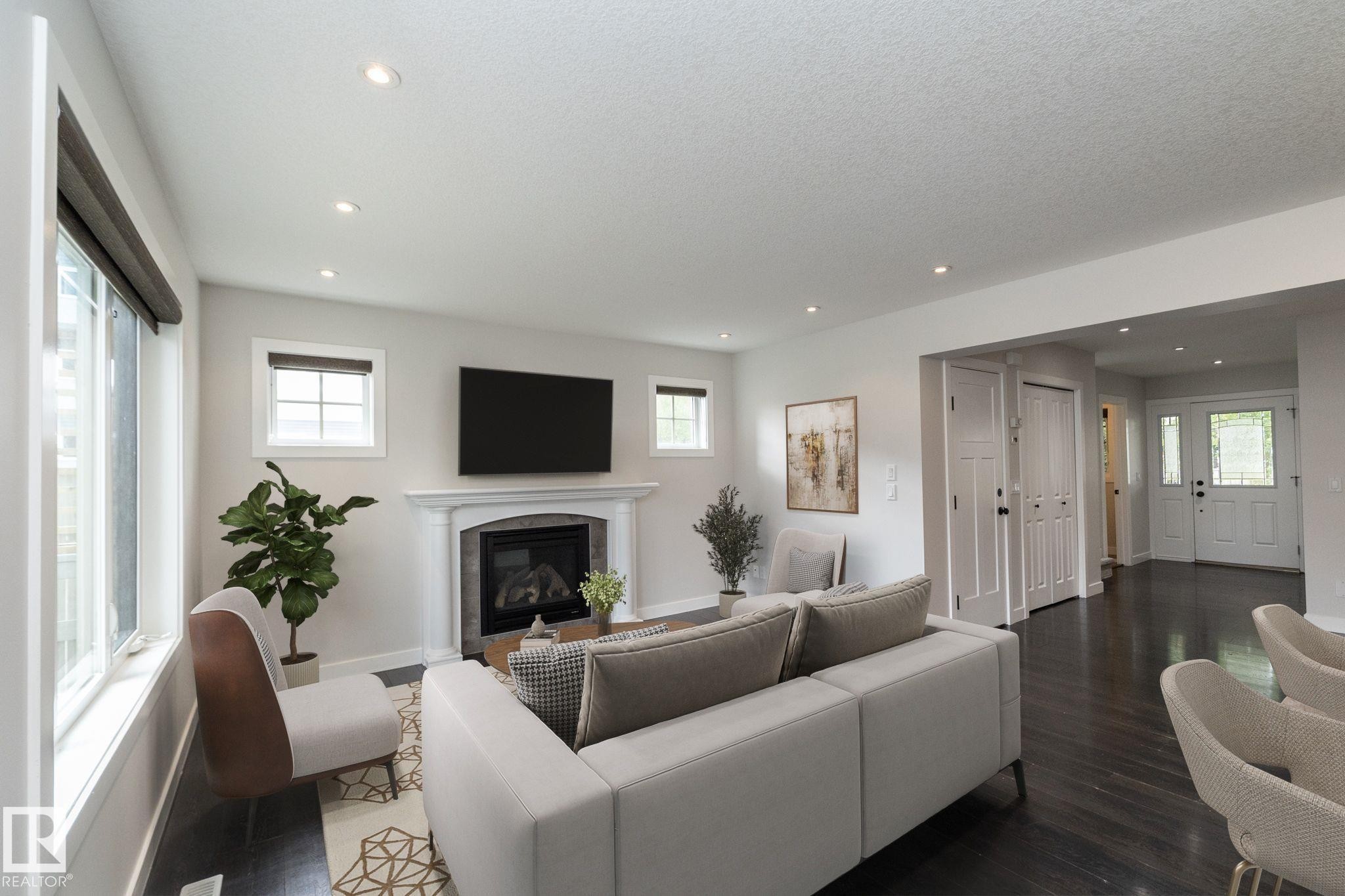 Recessed lighting, dark wood-finish flooring, white trim, fireplace with a mantel, and a white paneled entry door - 55 Michigan Street, Devon, AB
