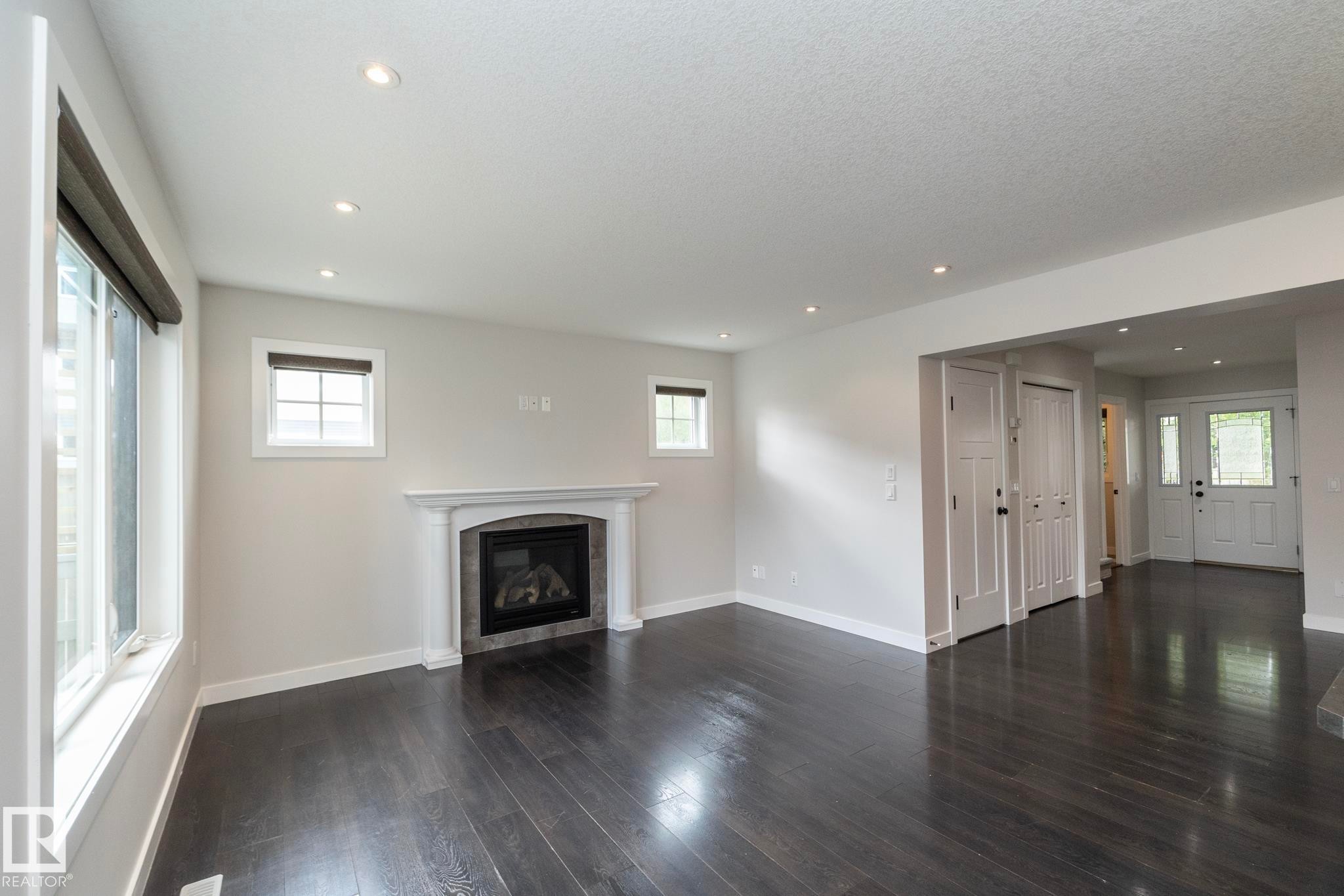 Recessed lighting, wood-finish flooring, a fireplace with a stone surround, and multiple windows - 55 Michigan Street, Devon, AB