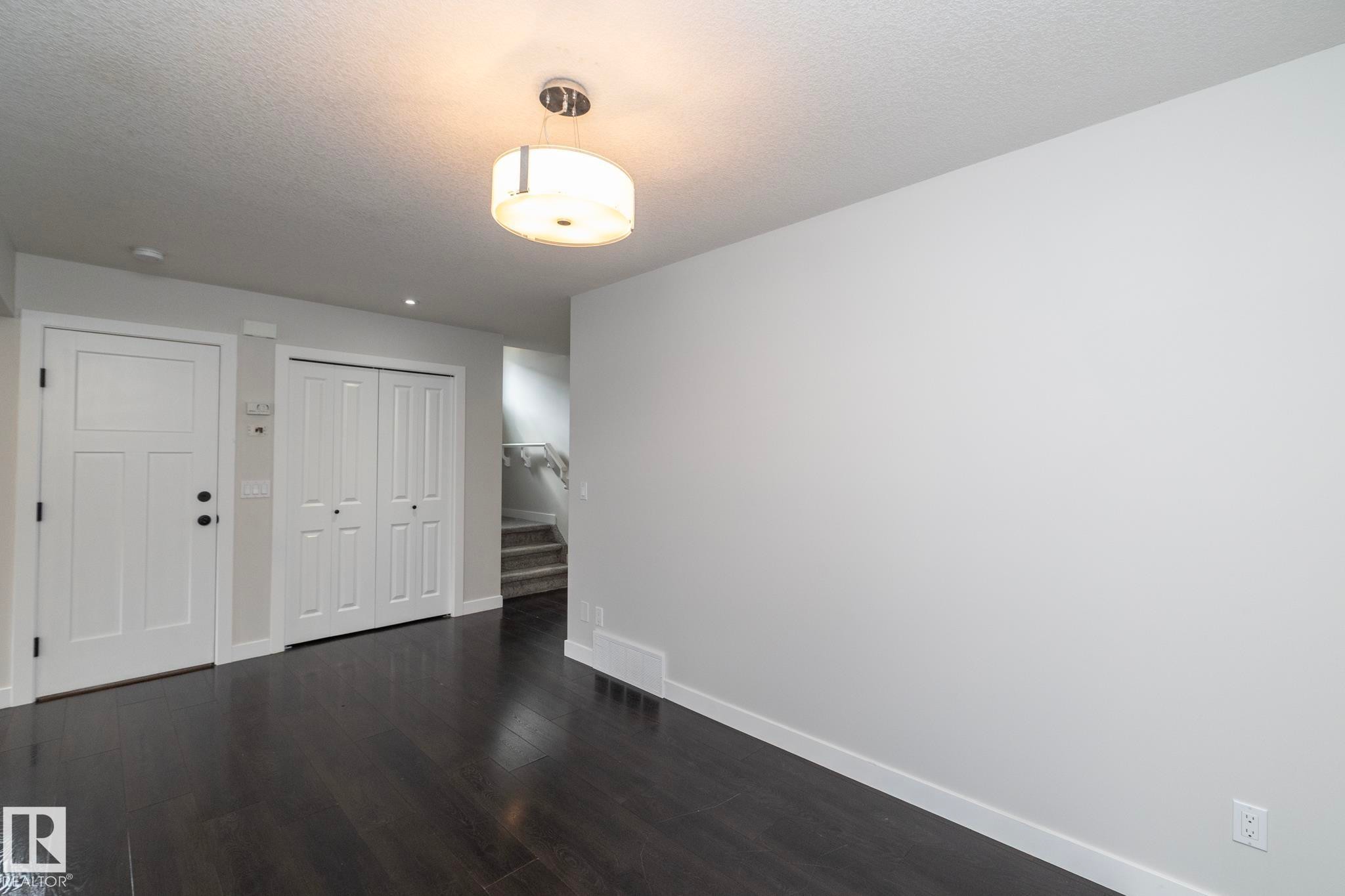 Dark wood-finish flooring, white paneled doors, and a contemporary ceiling light fixture - 55 Michigan Street, Devon, AB