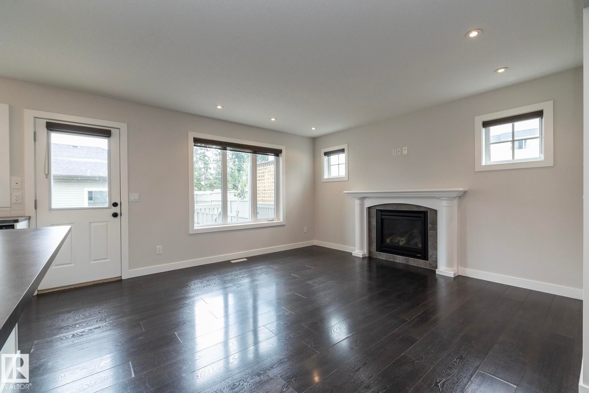 Wood-finish flooring, recessed lighting, and a white mantel fireplace with tile surround - 55 Michigan Street, Devon, AB