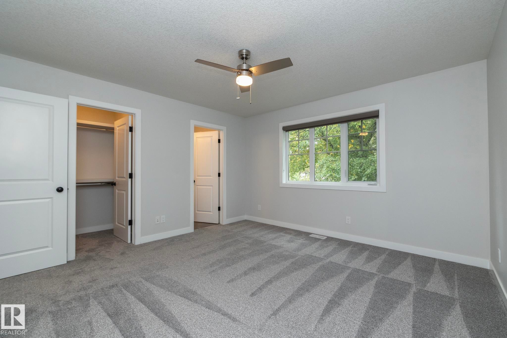 Room featuring textured carpeting, a flush-mount ceiling fan, and a window with blinds - 55 Michigan Street, Devon, AB