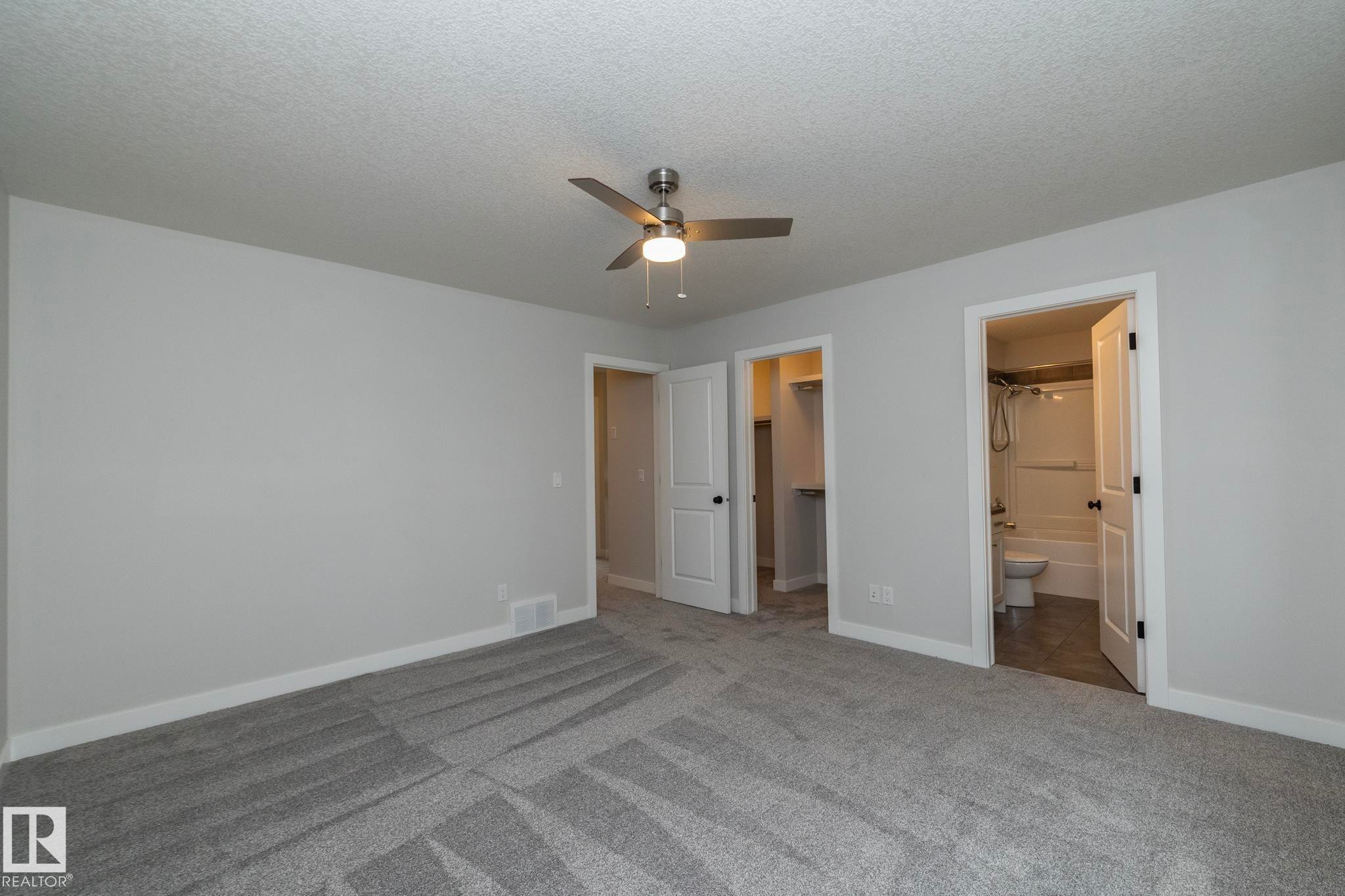 Plush carpeting, neutral wall tones, modern ceiling fan, recessed closet space, and a full bathroom with a tub and shower combination - 55 Michigan Street, Devon, AB