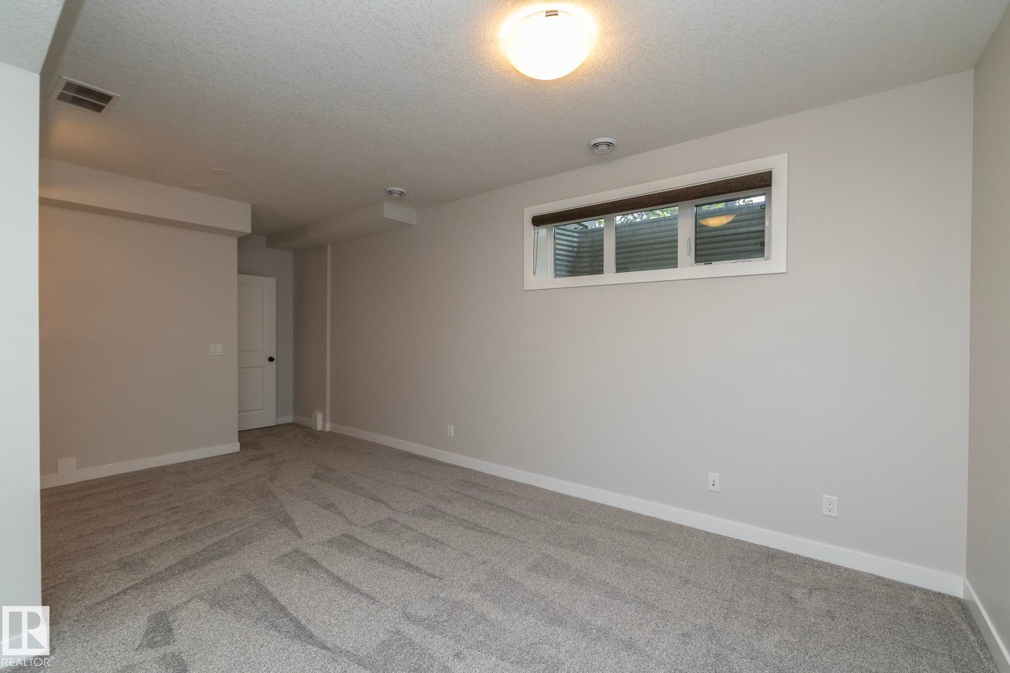 Recessed window with white trim, flush-mount ceiling light, light-toned walls, and patterned carpeting - 55 Michigan Street, Devon, AB