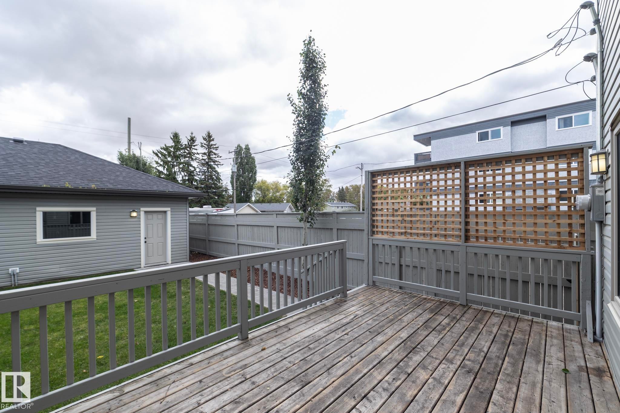 Expansive wooden deck with a privacy lattice screen and a gray painted fence - 55 Michigan Street, Devon, AB
