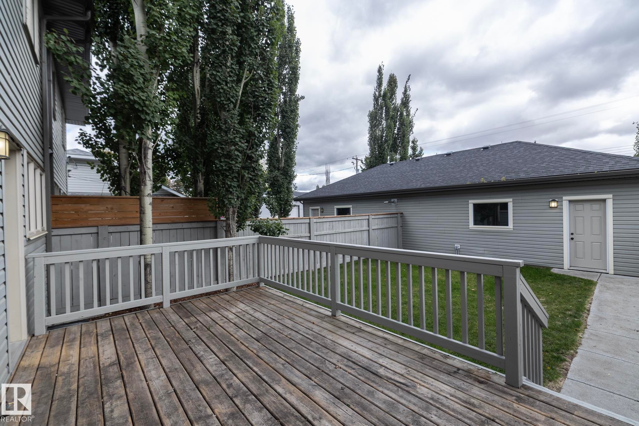 Expansive wood deck with painted railings, surrounded by a wood privacy fence - 55 Michigan Street, Devon, AB