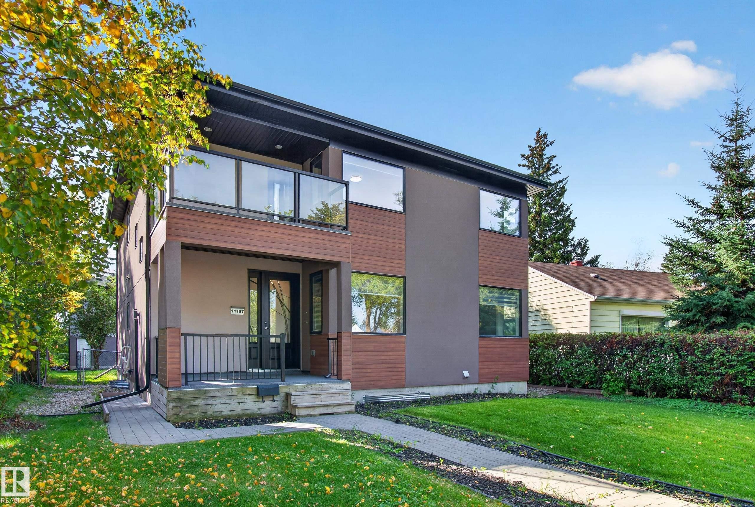 Modern architectural design featuring a second-story balcony with glass railing, a covered entryway, and a combination of wood-look siding and smooth panels - 11167 62 Avenue Nw, Edmonton, AB