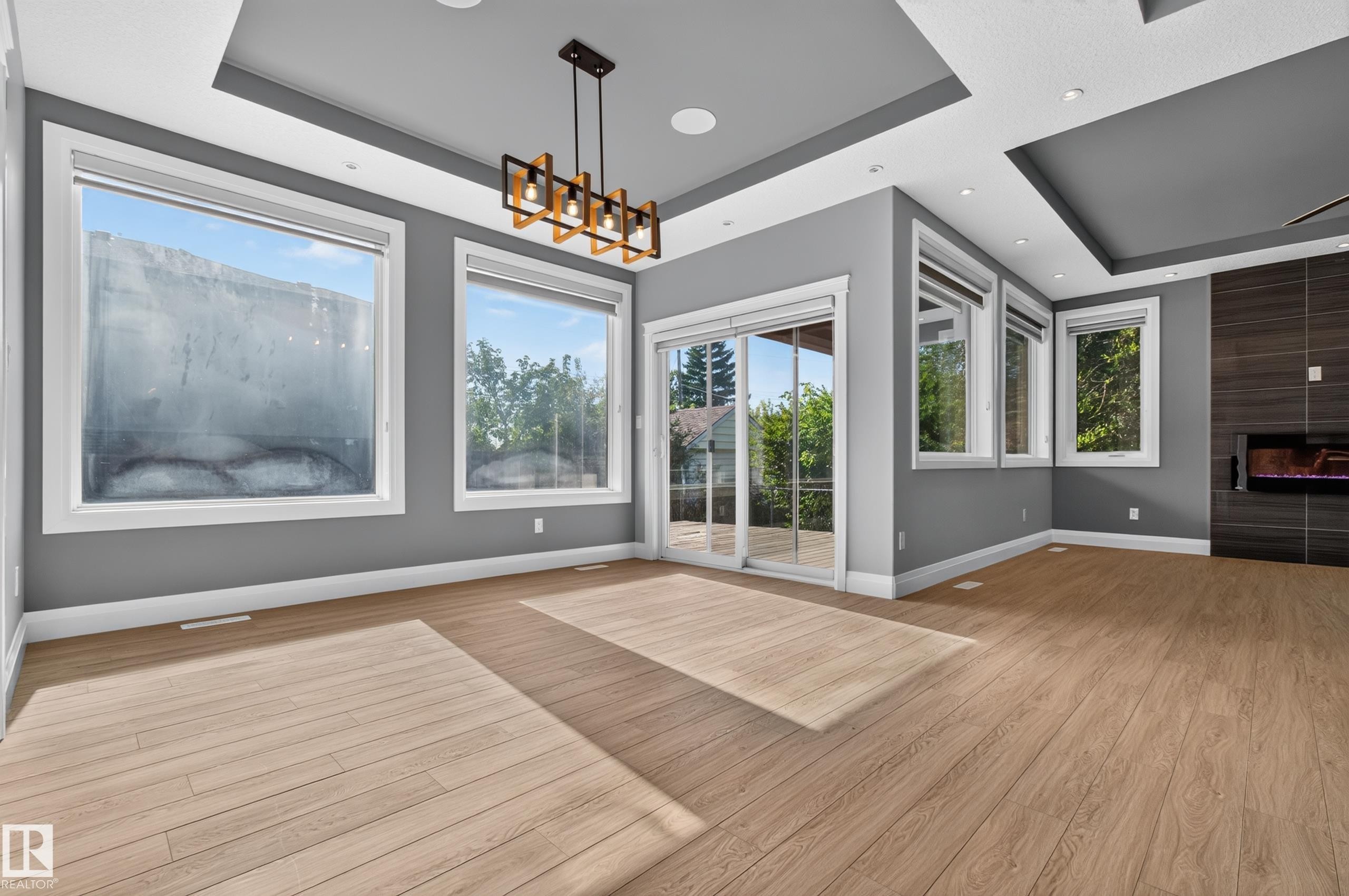 Wood-finish flooring, recessed lighting, contemporary chandelier, gas fireplace, and sliding glass doors to exterior - 11167 62 Avenue Nw, Edmonton, AB