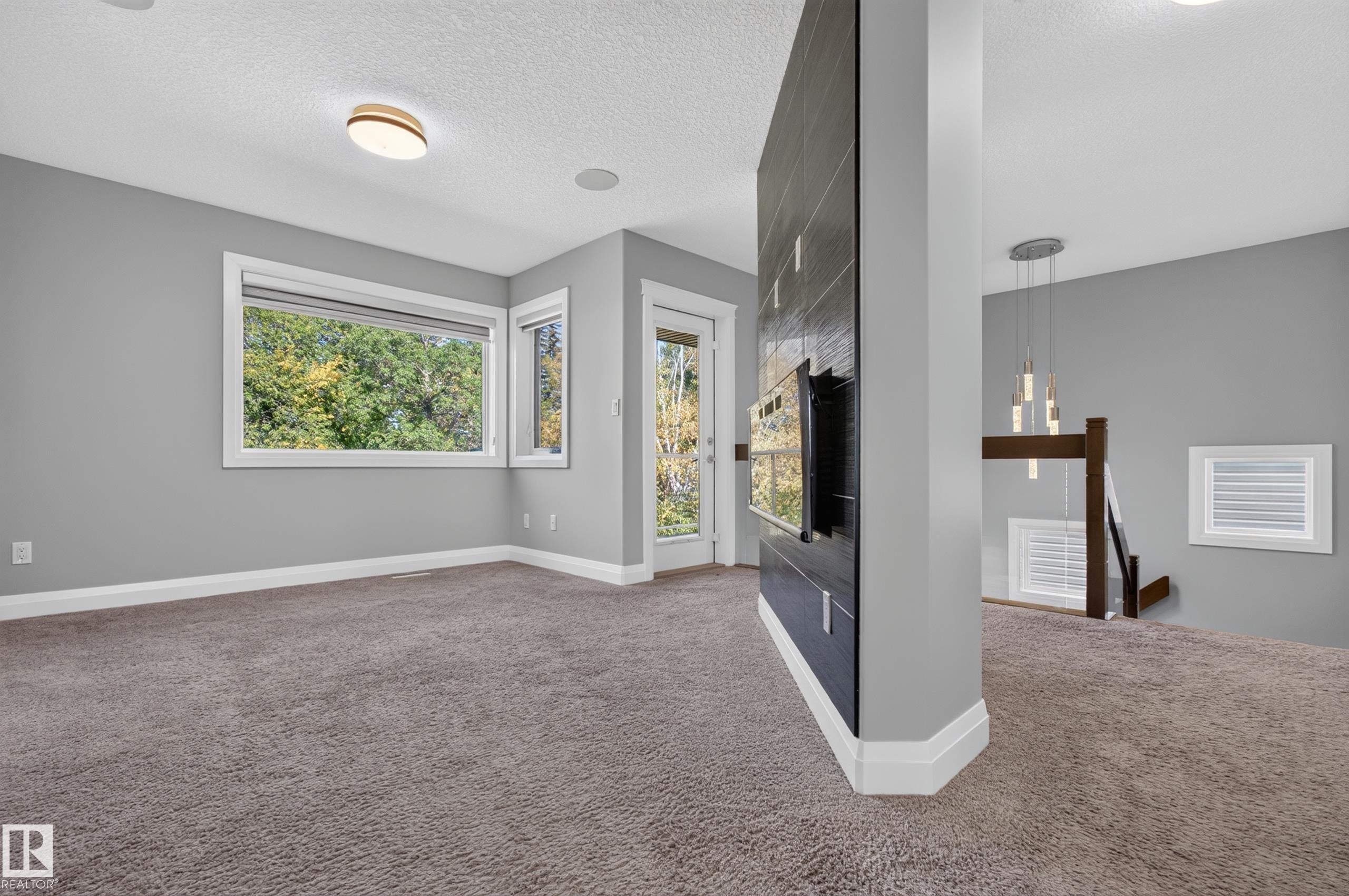 Wall-mounted oven set into a dark-tiled feature wall, complemented by a contemporary chandelier and recessed ceiling lighting - 11167 62 Avenue Nw, Edmonton, AB