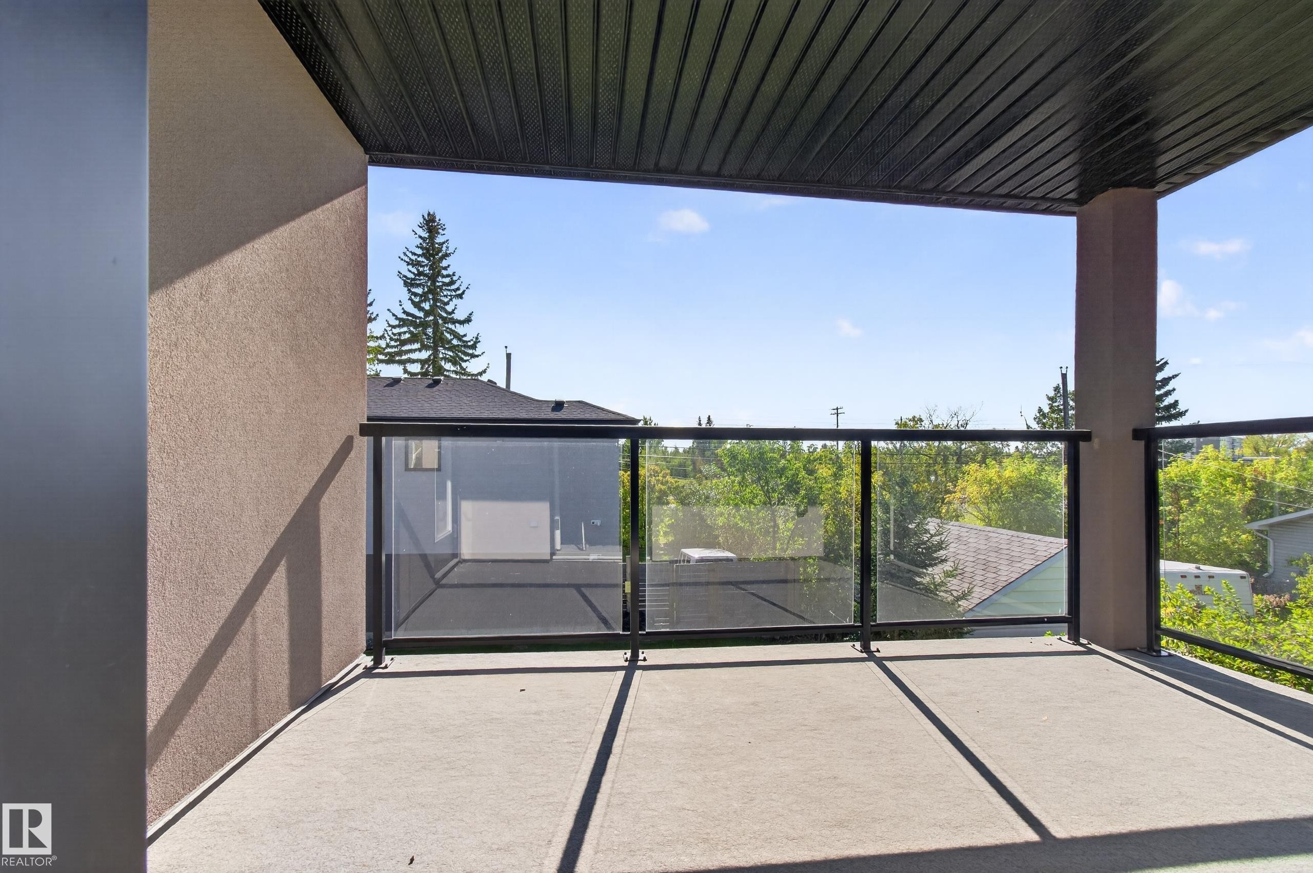 Spacious balcony with concrete flooring, glass panel railing, and a black soffit ceiling - 11167 62 Avenue Nw, Edmonton, AB