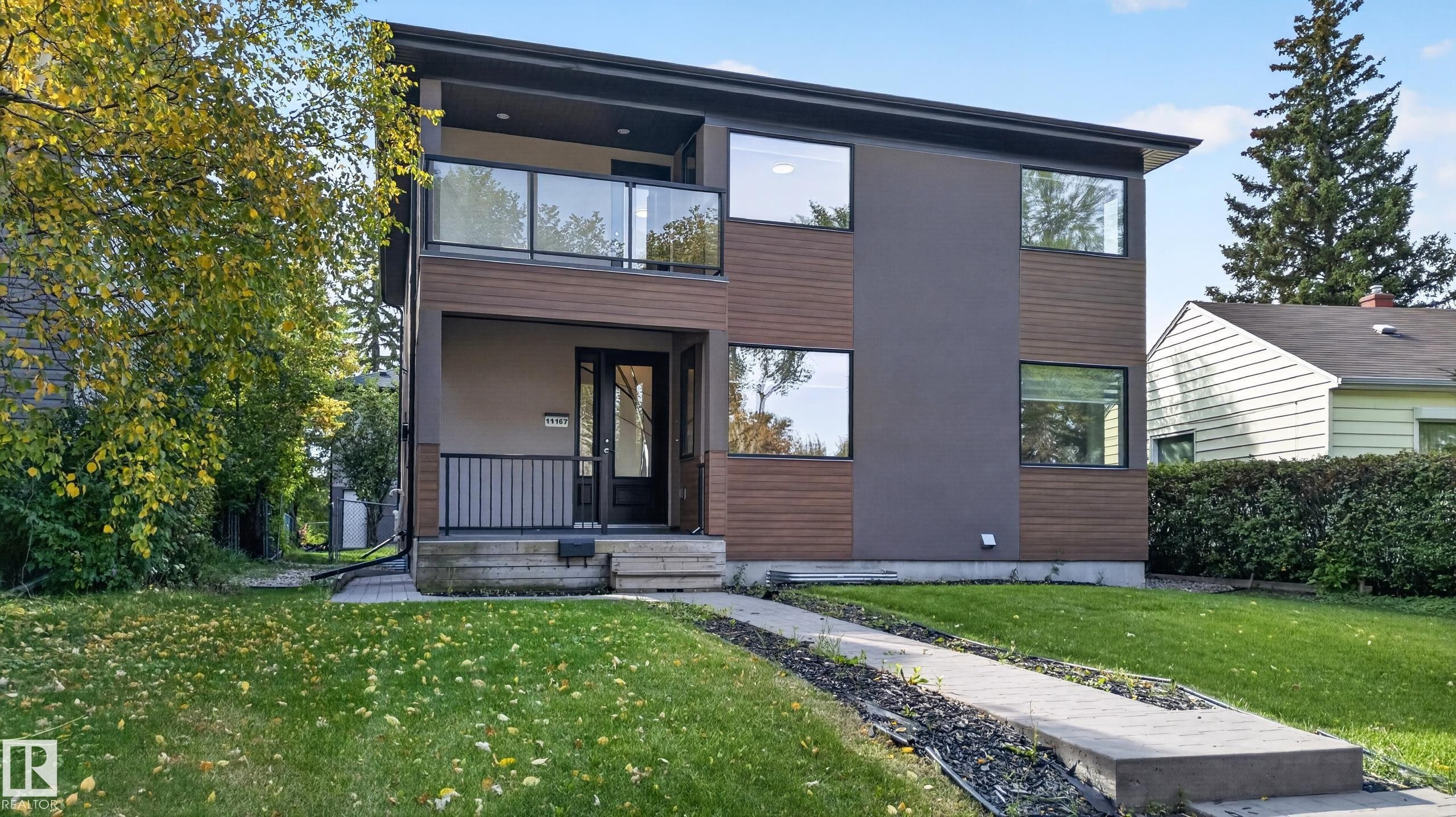 Contemporary exterior featuring a two-story design, a balcony with glass railings, large windows, and a combination of smooth and textured siding - 11167 62 Avenue Nw, Edmonton, AB