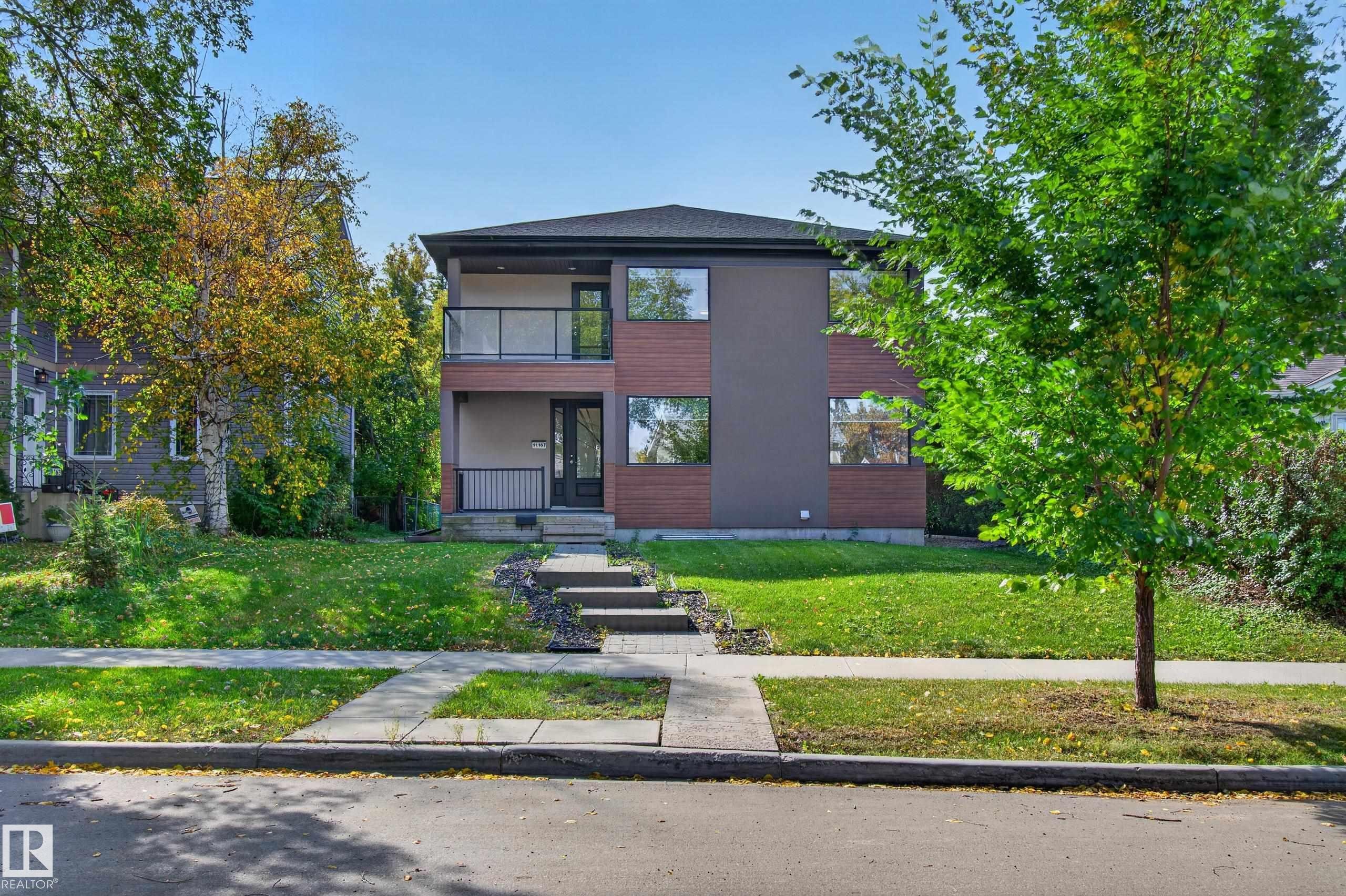 Contemporary exterior with mixed-material facade, featuring a second-story balcony with a glass railing, a covered entryway, and a stone walkway - 11167 62 Avenue Nw, Edmonton, AB