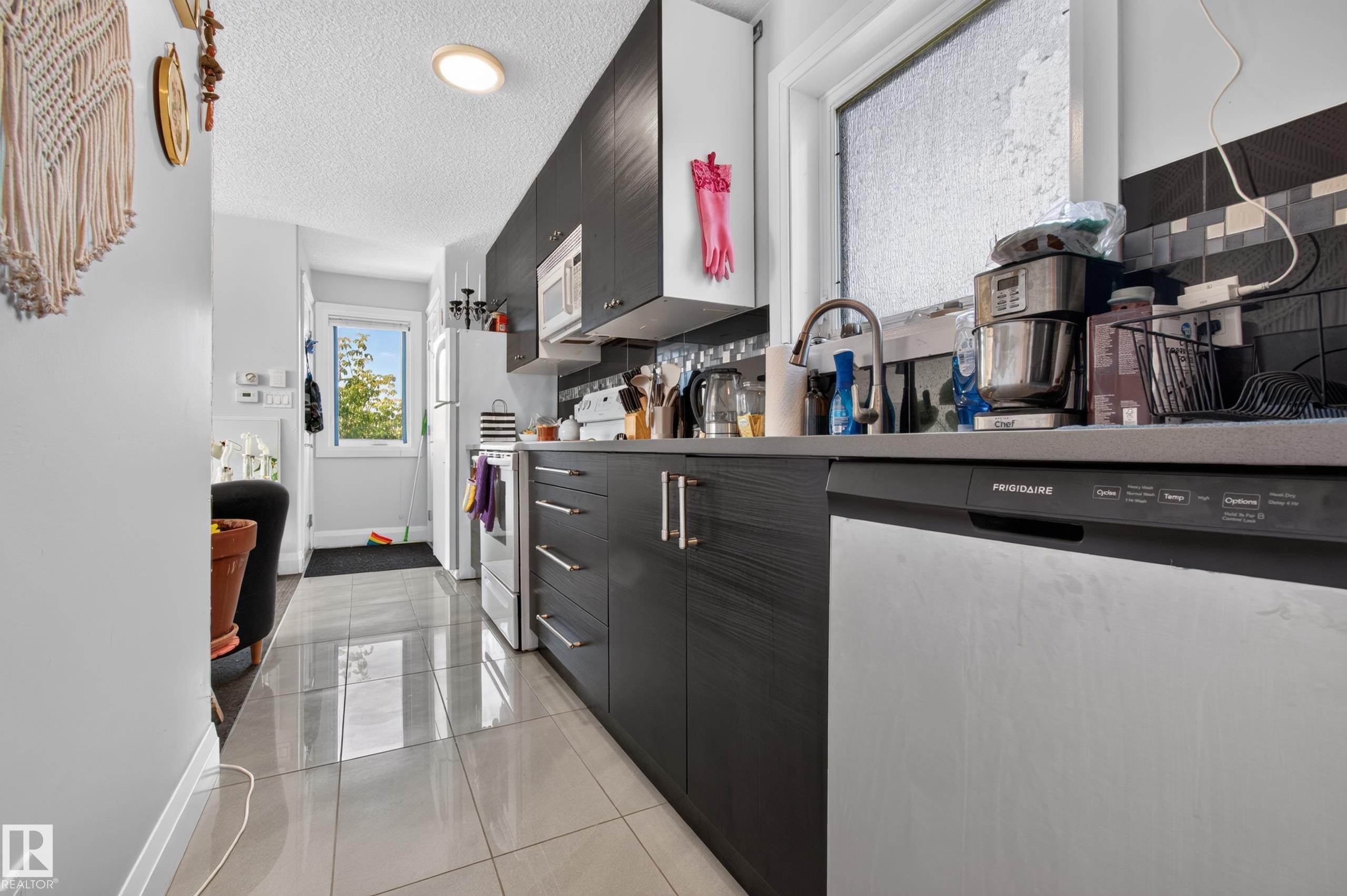 Contemporary kitchen featuring dark wood-finish cabinetry, stainless steel appliances, and a tile backsplash - 11167 62 Avenue Nw, Edmonton, AB