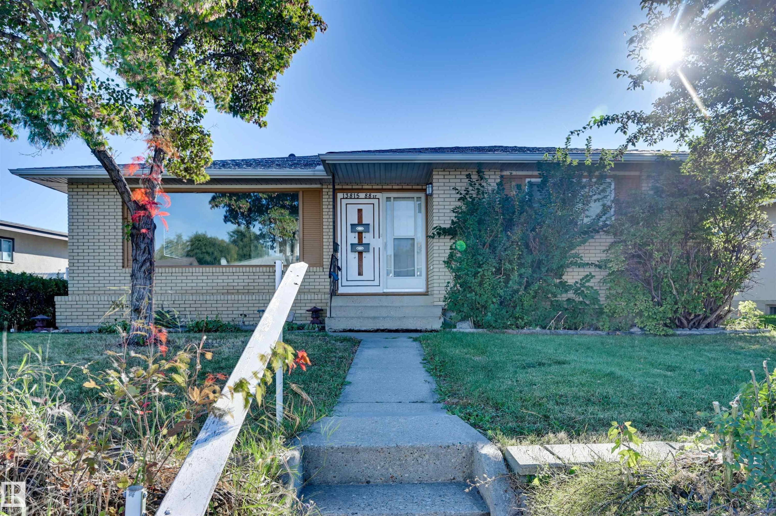 Brick exterior with a prominent front window and mature landscaping - 13815 88 Street Nw, Edmonton, AB