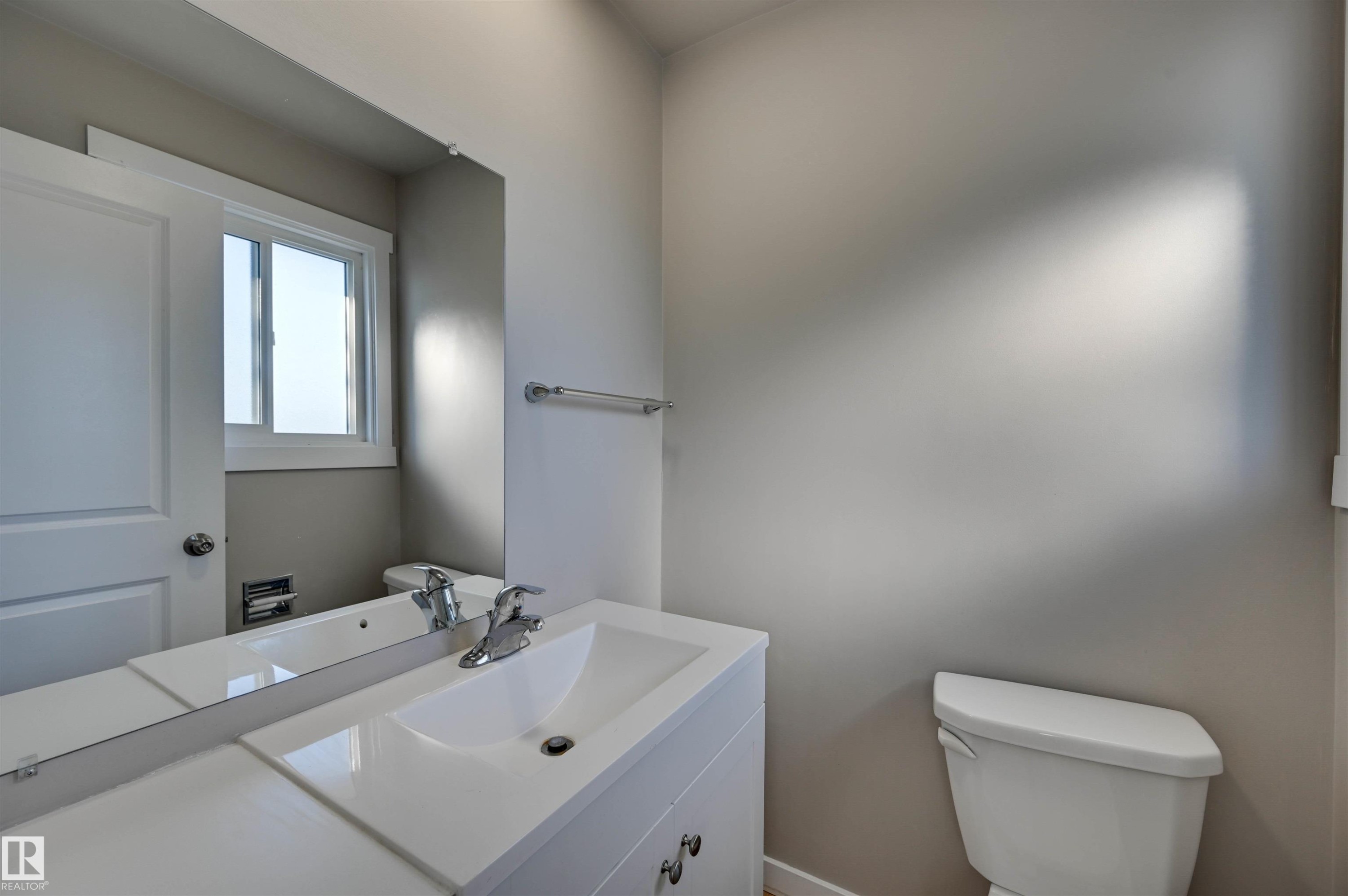 White vanity with an integrated sink, chrome faucet, and expansive mirror - 13815 88 Street Nw, Edmonton, AB