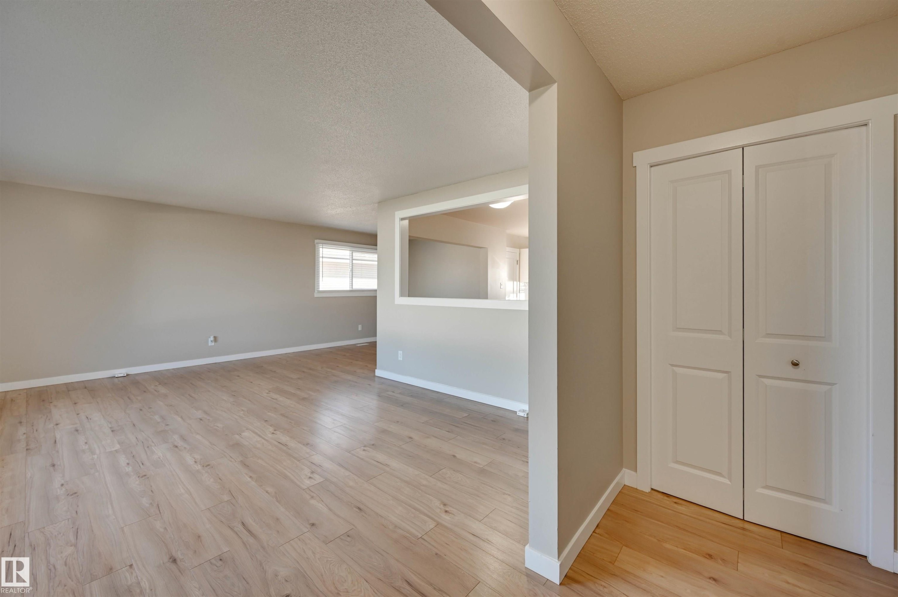 Wood-finish flooring, white bifold closet doors, and a pass-through opening - 13815 88 Street Nw, Edmonton, AB