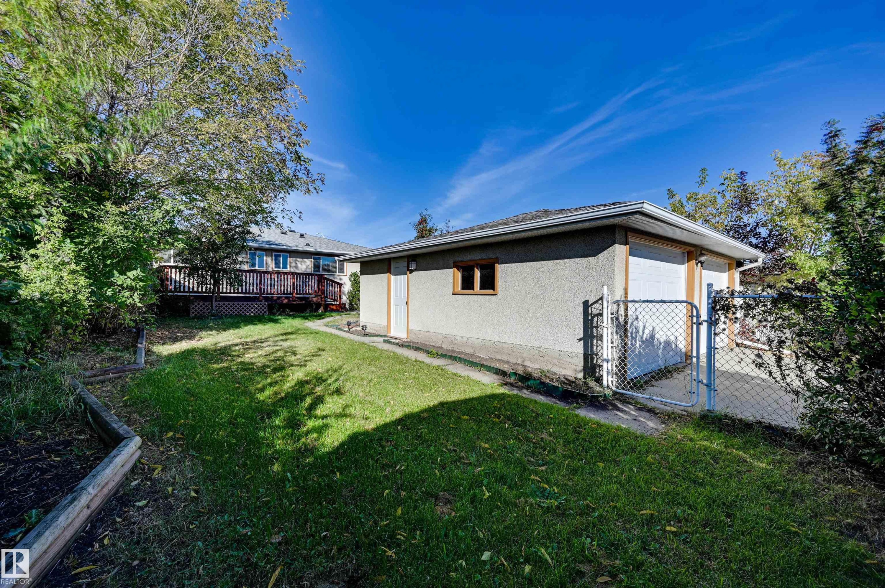 Detached garage with two white garage doors, an access door, and a single window - 13815 88 Street Nw, Edmonton, AB