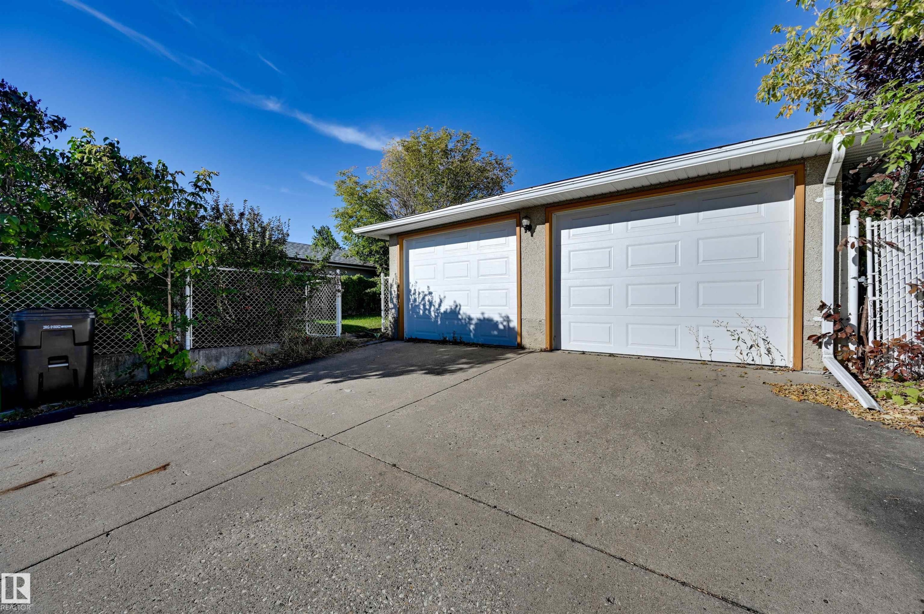 Two-car attached garage with white panel doors, wood-finish trim, and a concrete driveway - 13815 88 Street Nw, Edmonton, AB