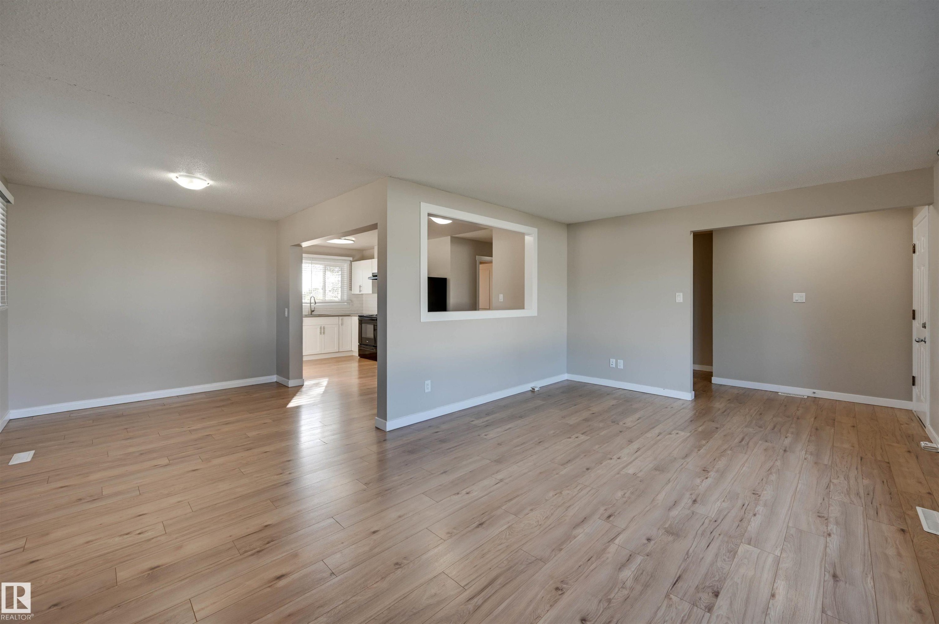 Expansive room featuring wood-finish flooring, neutral wall tones, and recessed lighting - 13815 88 Street Nw, Edmonton, AB