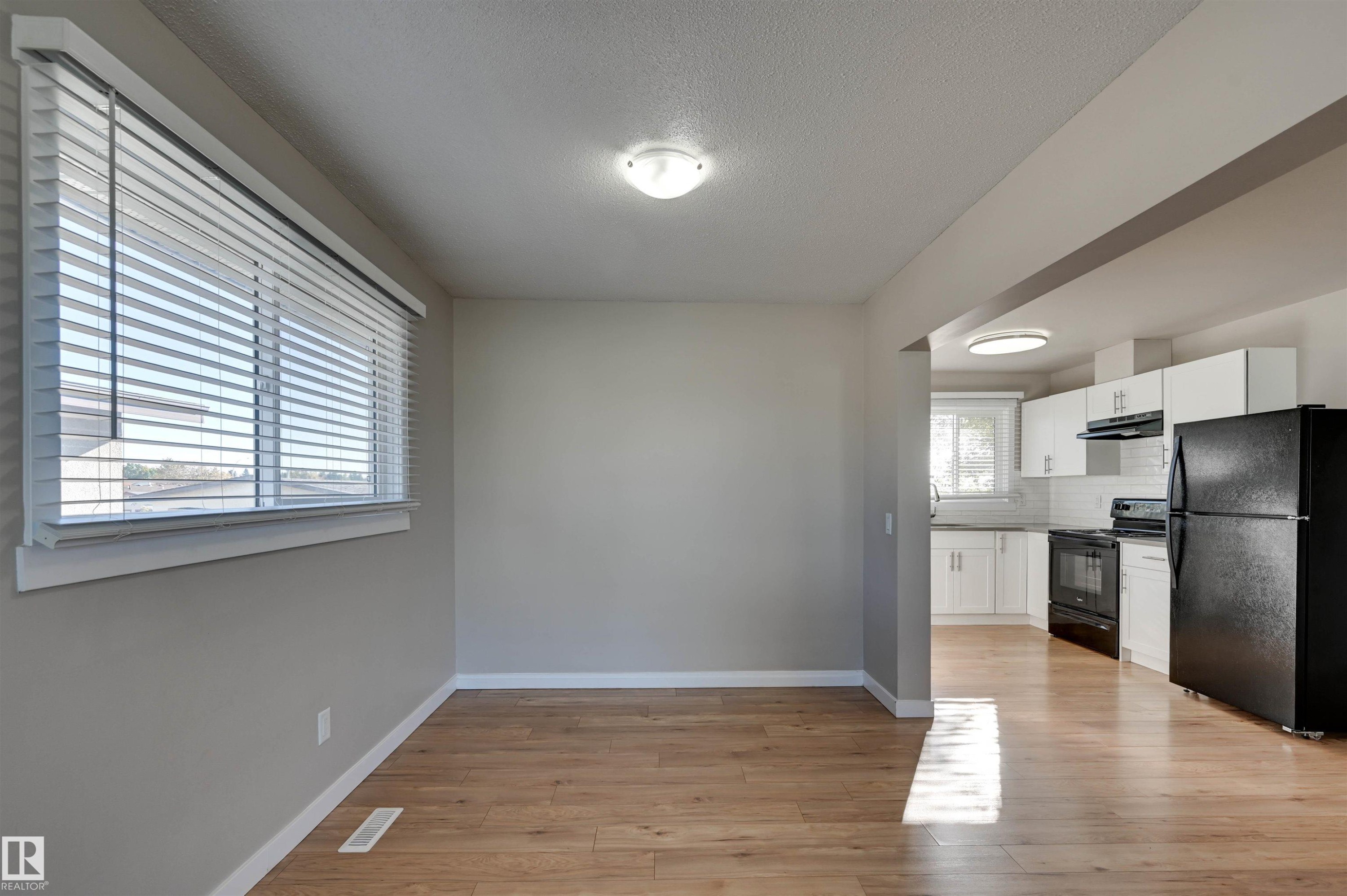 Bright interior with wood-finish flooring, a large window with blinds, and recessed lighting - 13815 88 Street Nw, Edmonton, AB