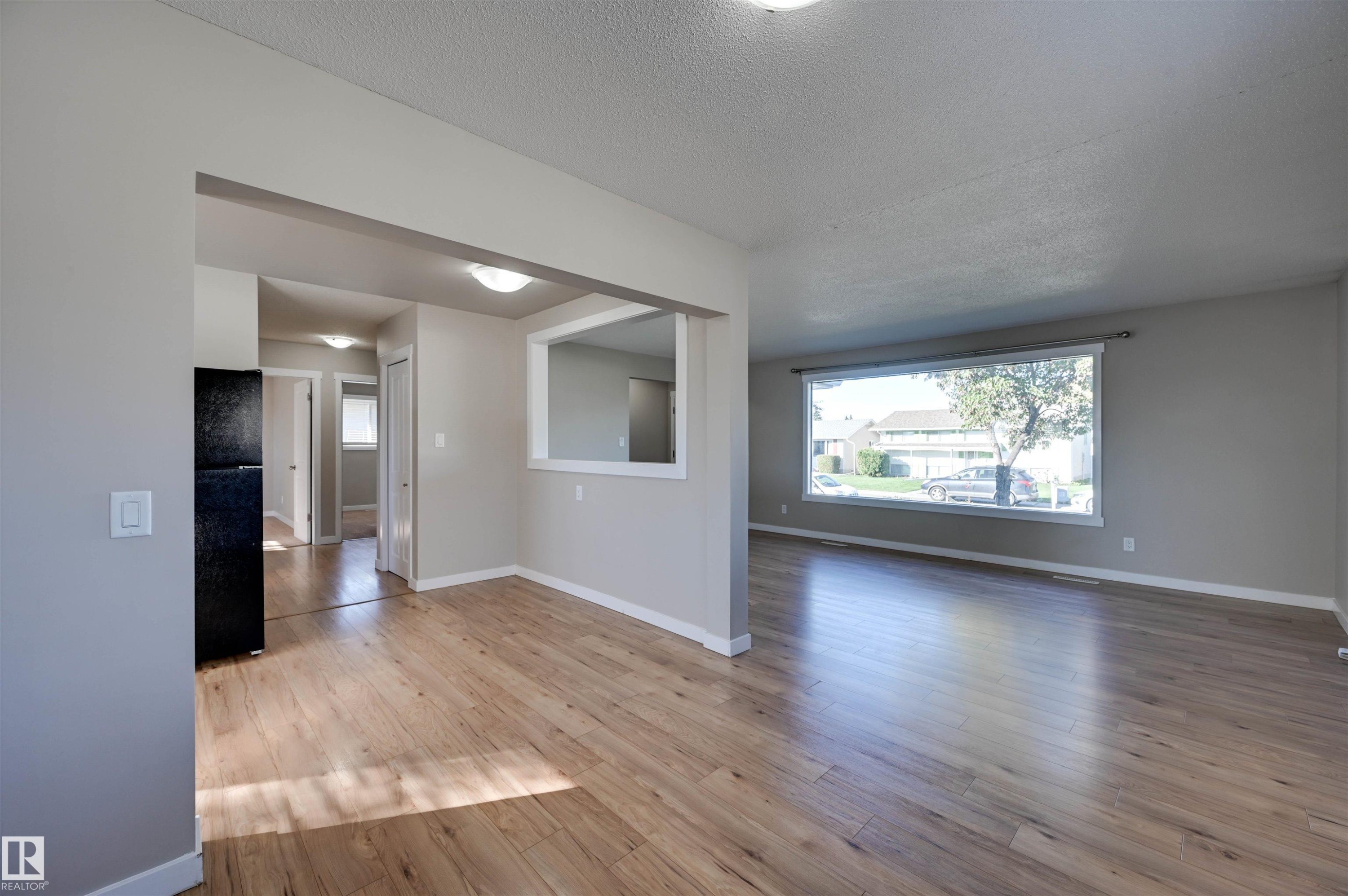 Wood-finish flooring throughout, neutral paint scheme, large window, and recessed lighting - 13815 88 Street Nw, Edmonton, AB