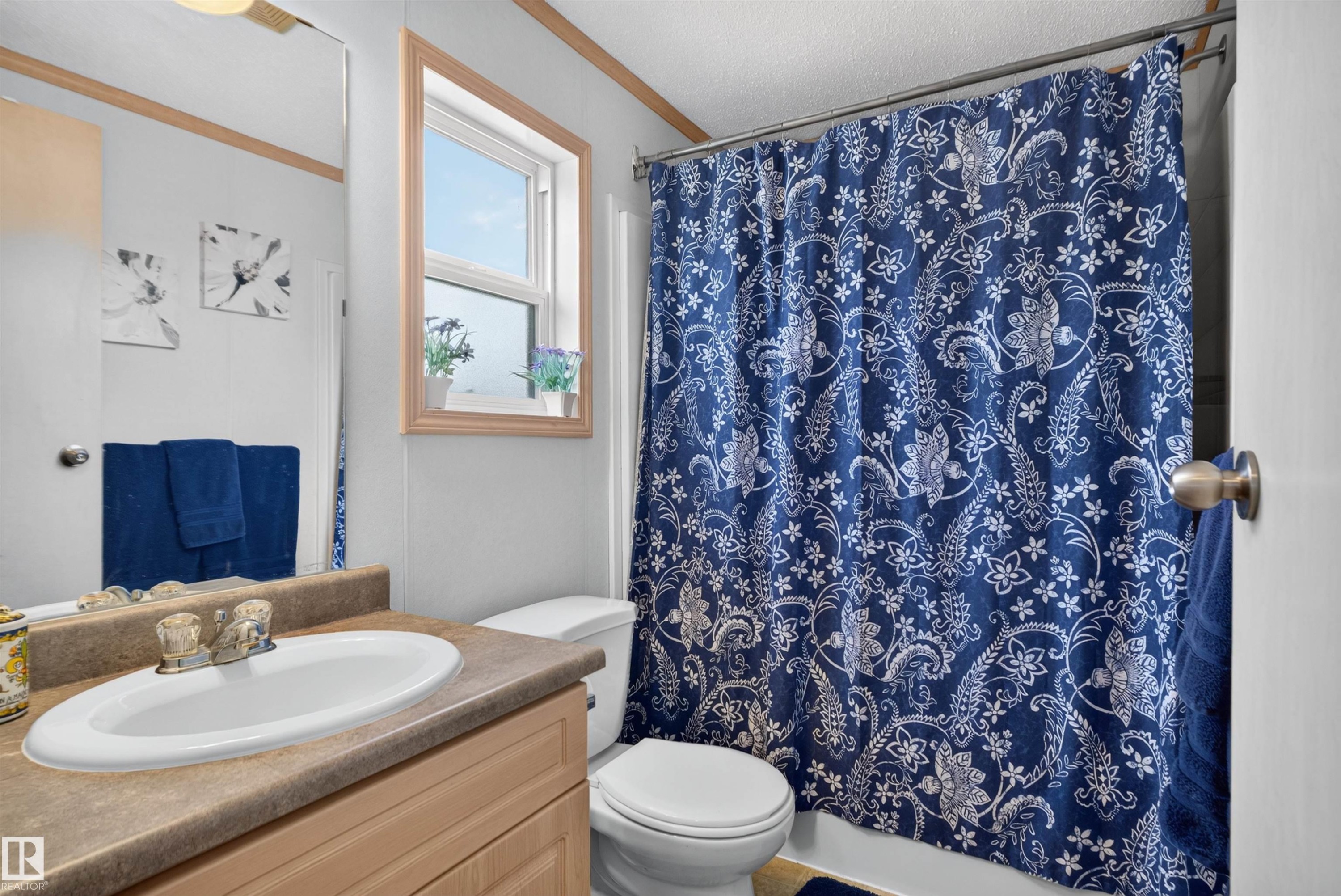 Vanity with an oval sink, light wood-finish cabinetry, and a window with wood trim - 1405 53222 Range Road 272, Rural Parkland County, AB