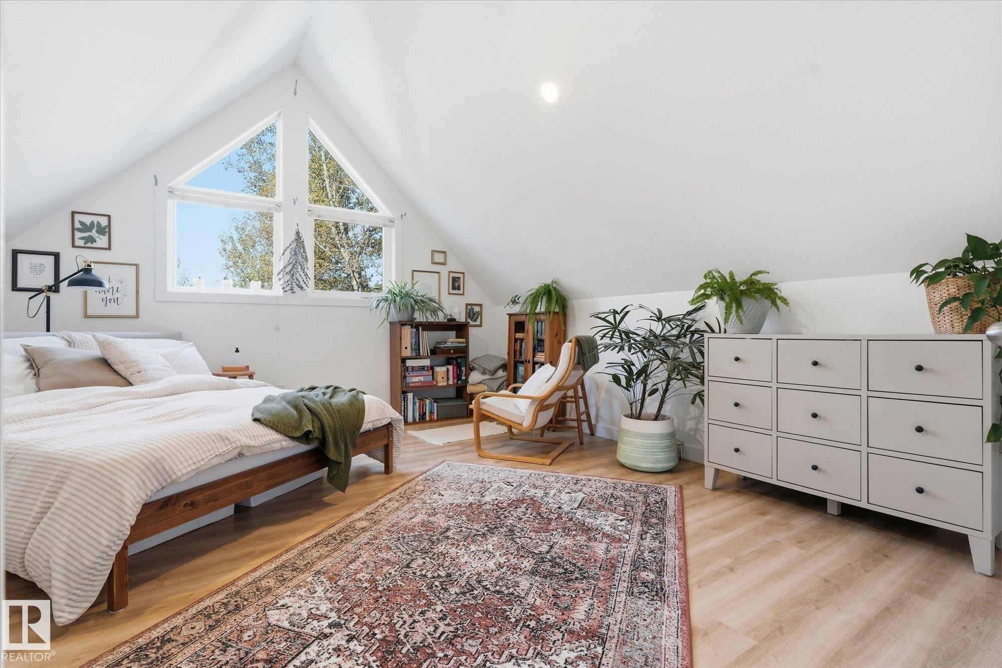 Vaulted ceiling featuring a large triangular window, wood-finish flooring, and a white dresser with nine drawers - #45 53122 Rge Road 14, Rural Parkland County, AB