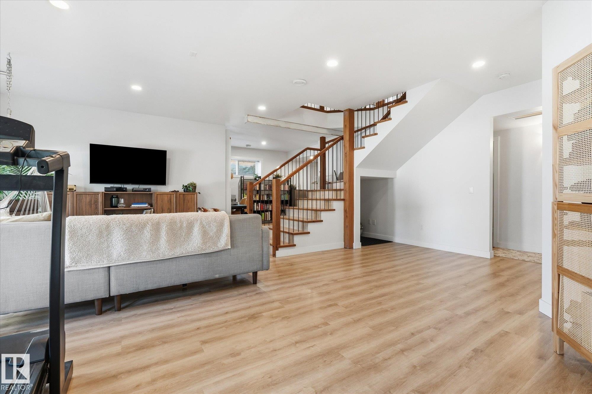 Wood-finish flooring, white walls, recessed lighting, and a prominent wood staircase with metal balusters - #45 53122 Rge Road 14, Rural Parkland County, AB
