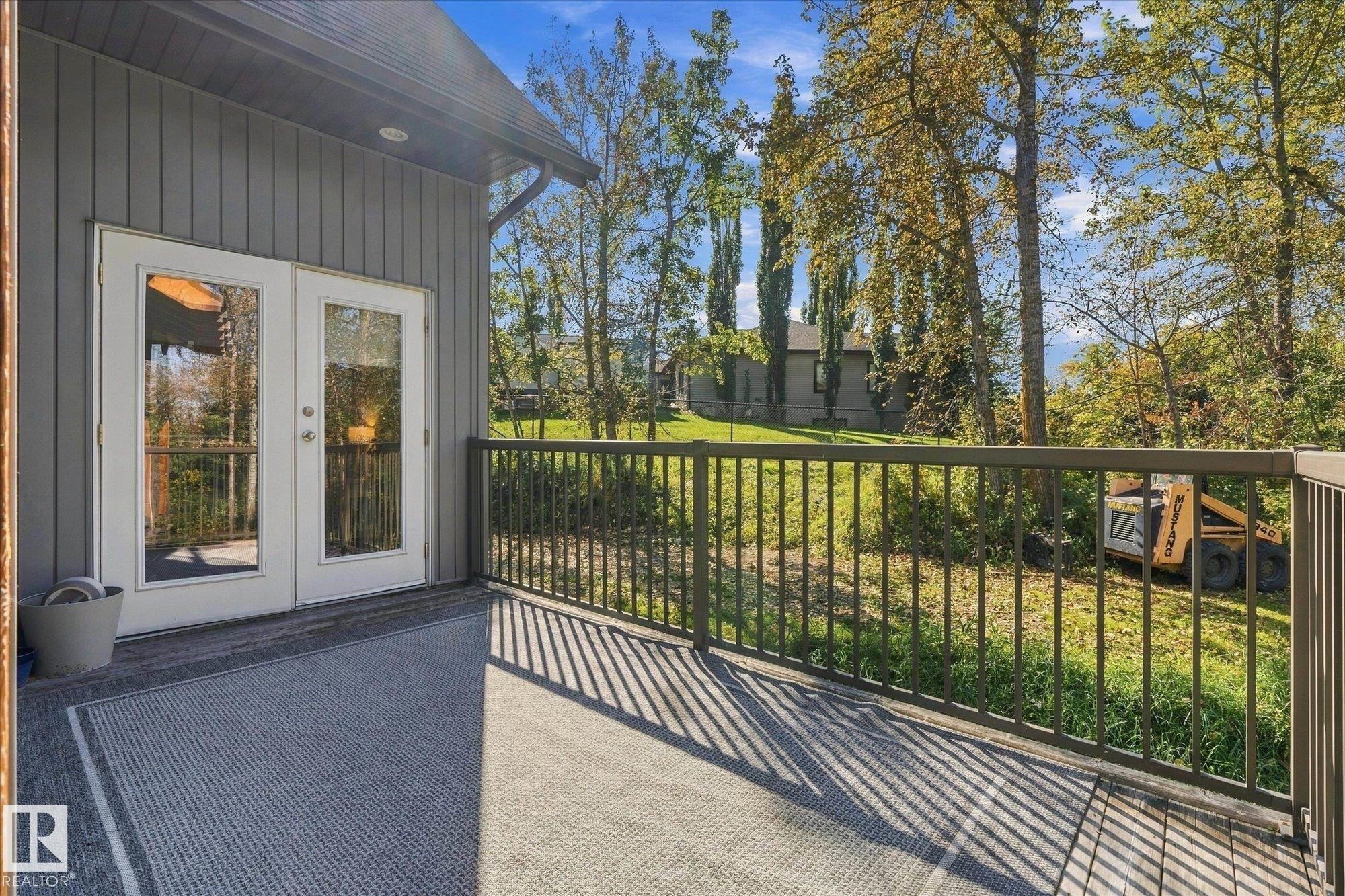 Outdoor deck with dark railing, white French doors, and gray vertical siding - #45 53122 Rge Road 14, Rural Parkland County, AB