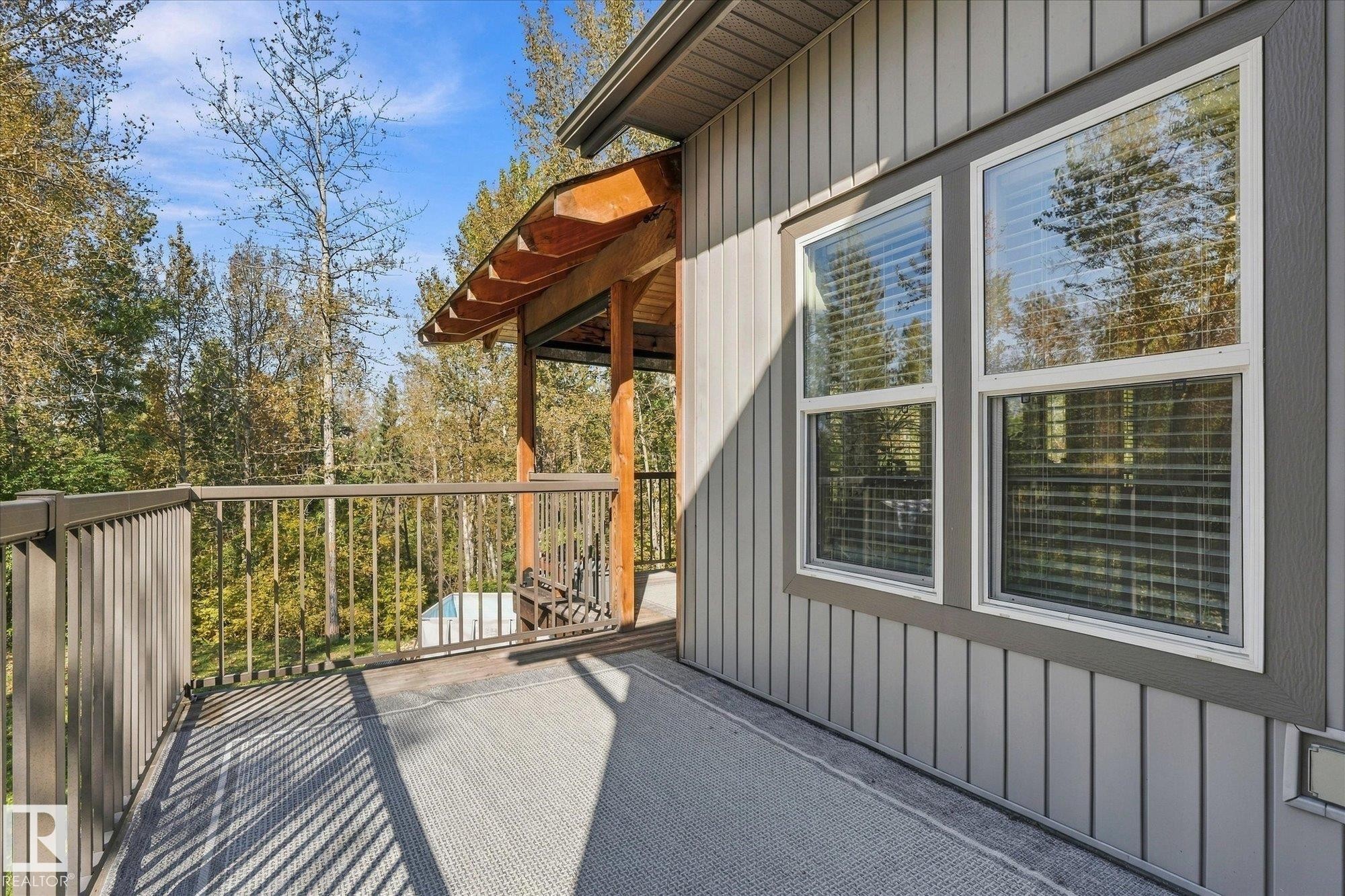 Exterior deck with metal railings and a wood-beamed covered section - #45 53122 Rge Road 14, Rural Parkland County, AB