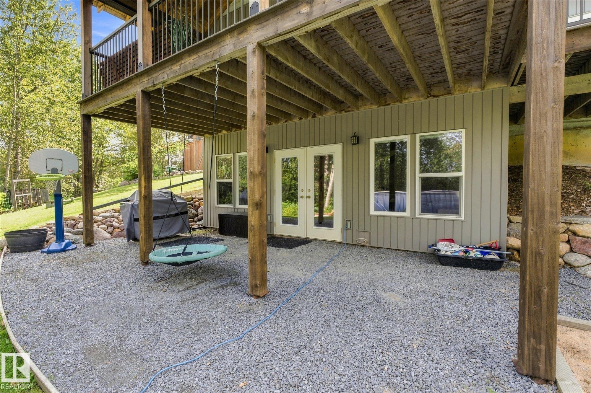 Expansive covered patio with wooden beam construction and gravel flooring, offering sheltered outdoor entertaining space - #45 53122 Rge Road 14, Rural Parkland County, AB