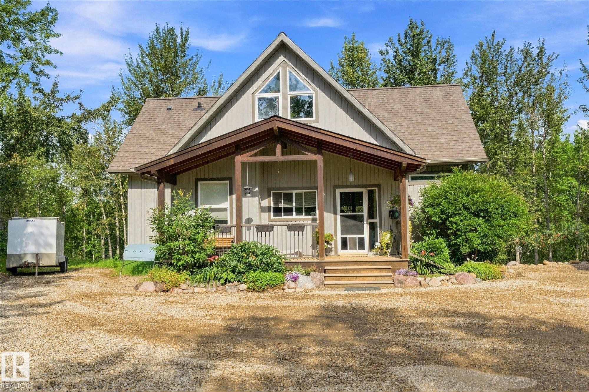 A-frame style residence featuring a covered porch with exposed beams, wood stairs, and a gravel driveway - #45 53122 Rge Road 14, Rural Parkland County, AB