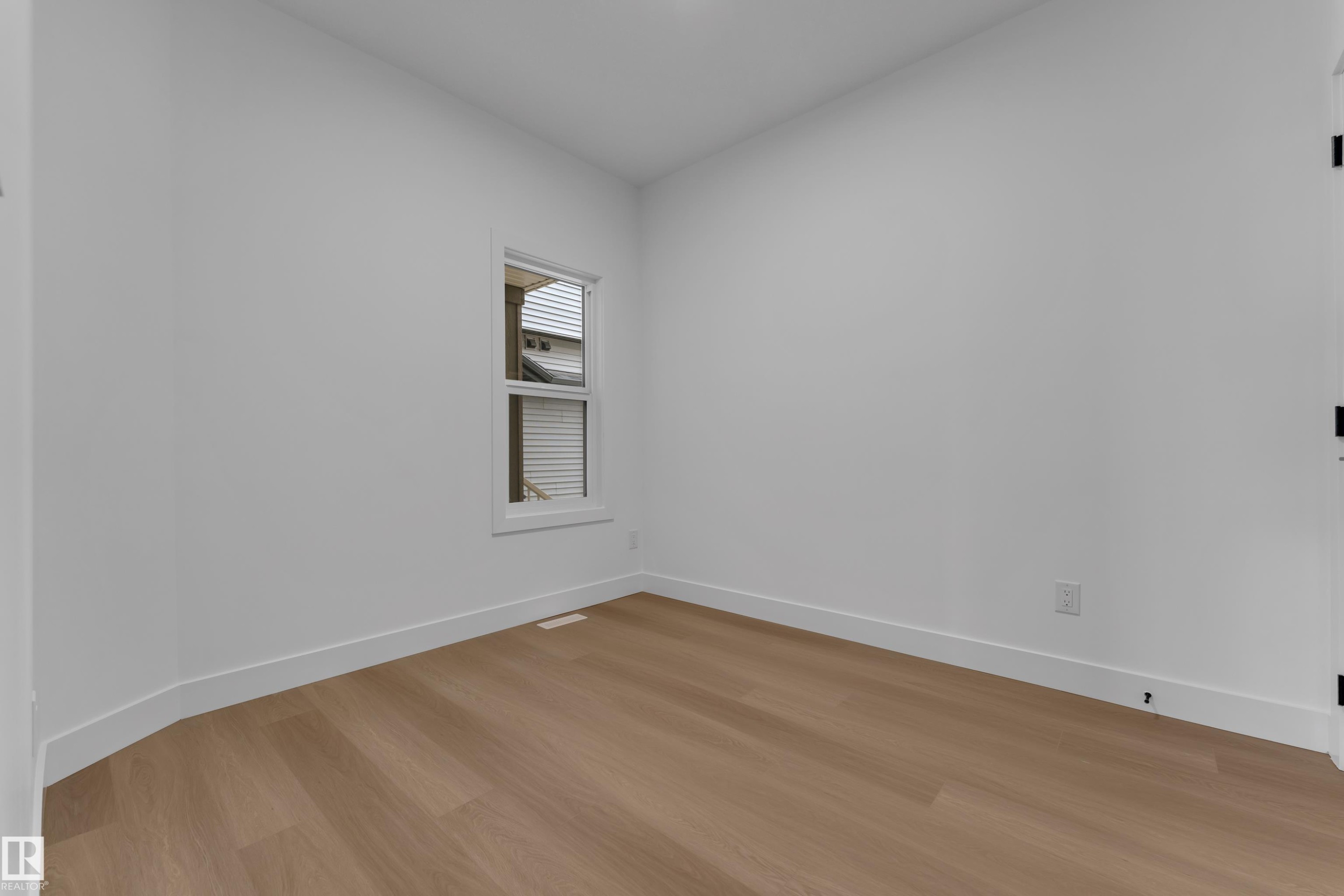 Bright interior with wood-finish flooring and a single white-framed window - 794 Bank Drive, Leduc, AB