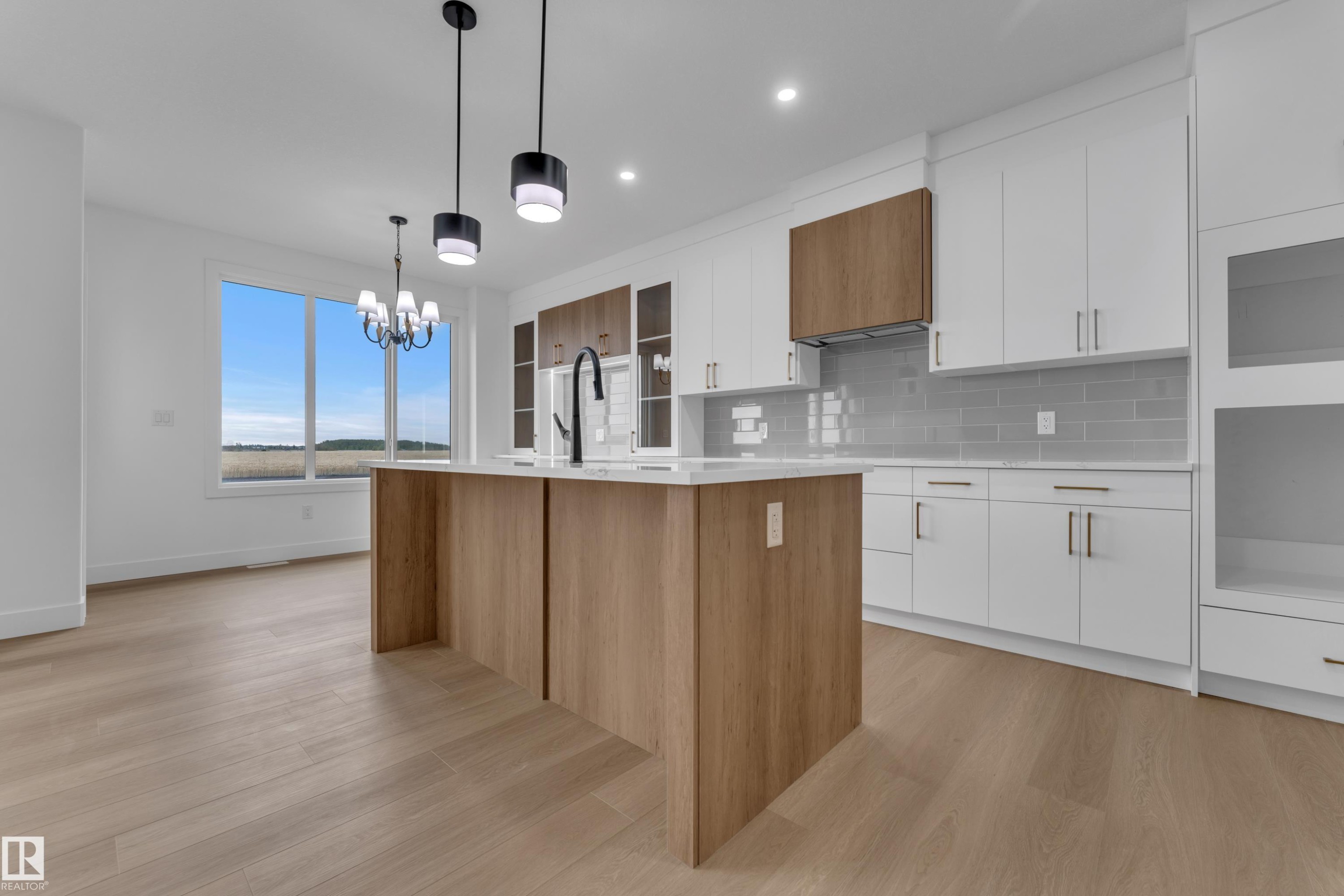 Modern kitchen featuring a wood-finish island, white cabinetry, light countertops, and a gray subway tile backsplash - 794 Bank Drive, Leduc, AB